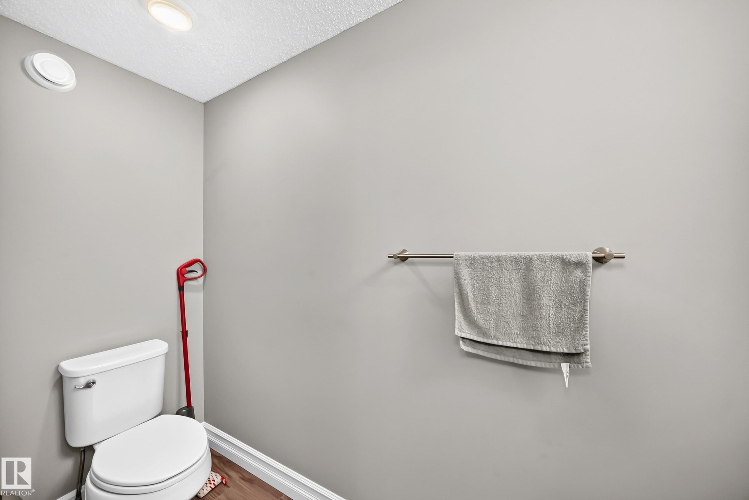 Recessed ceiling lighting illuminates a white toilet with a round bowl, complemented by wood-finish flooring - 415 Clareview Rd Nw Nw, Edmonton, AB - Indoor Photo Showing Bathroom