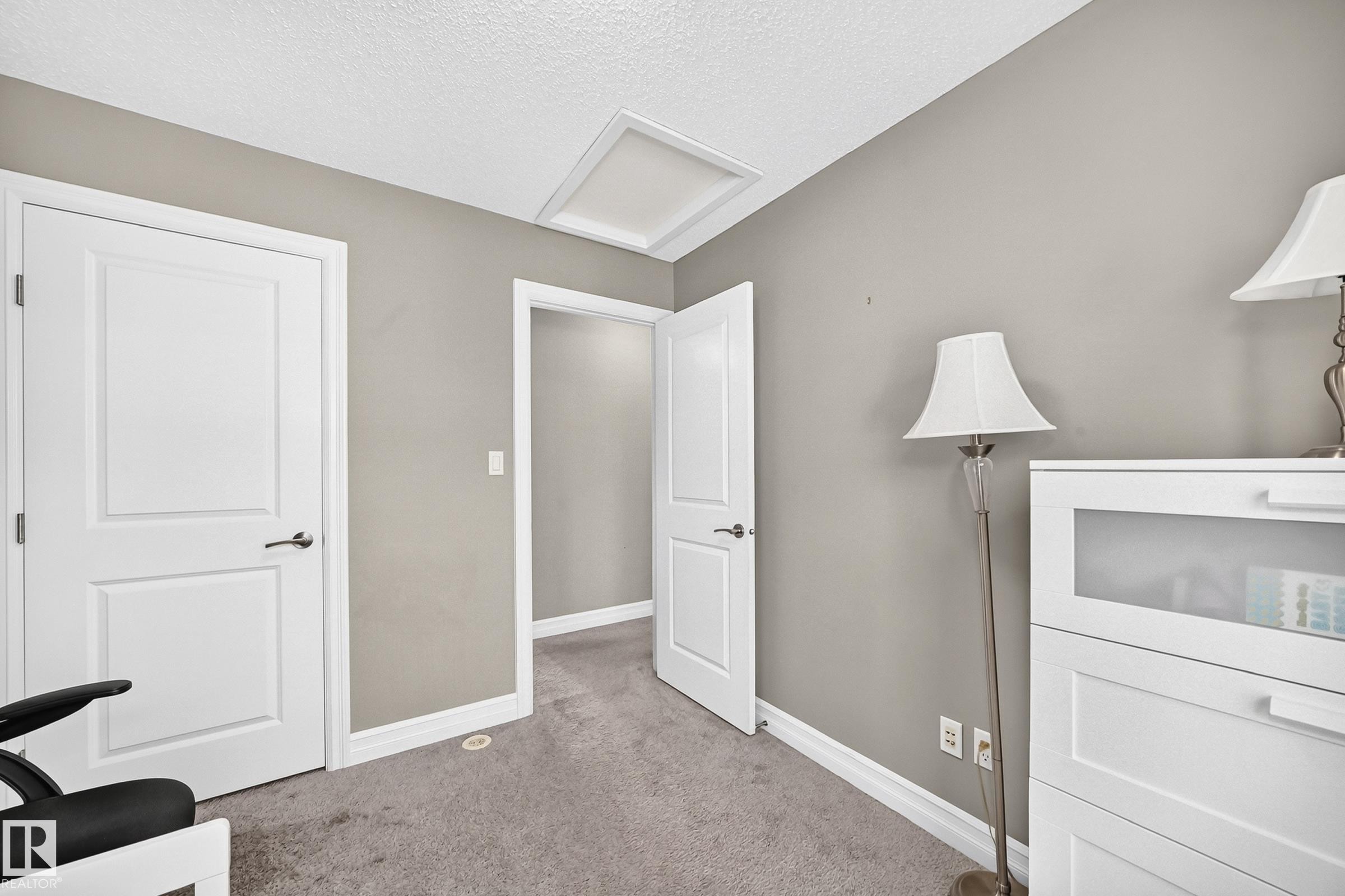 Neutral-toned room featuring a white paneled door, light gray walls, and gray carpeted flooring - 415 Clareview Rd Nw Nw, Edmonton, AB - Indoor