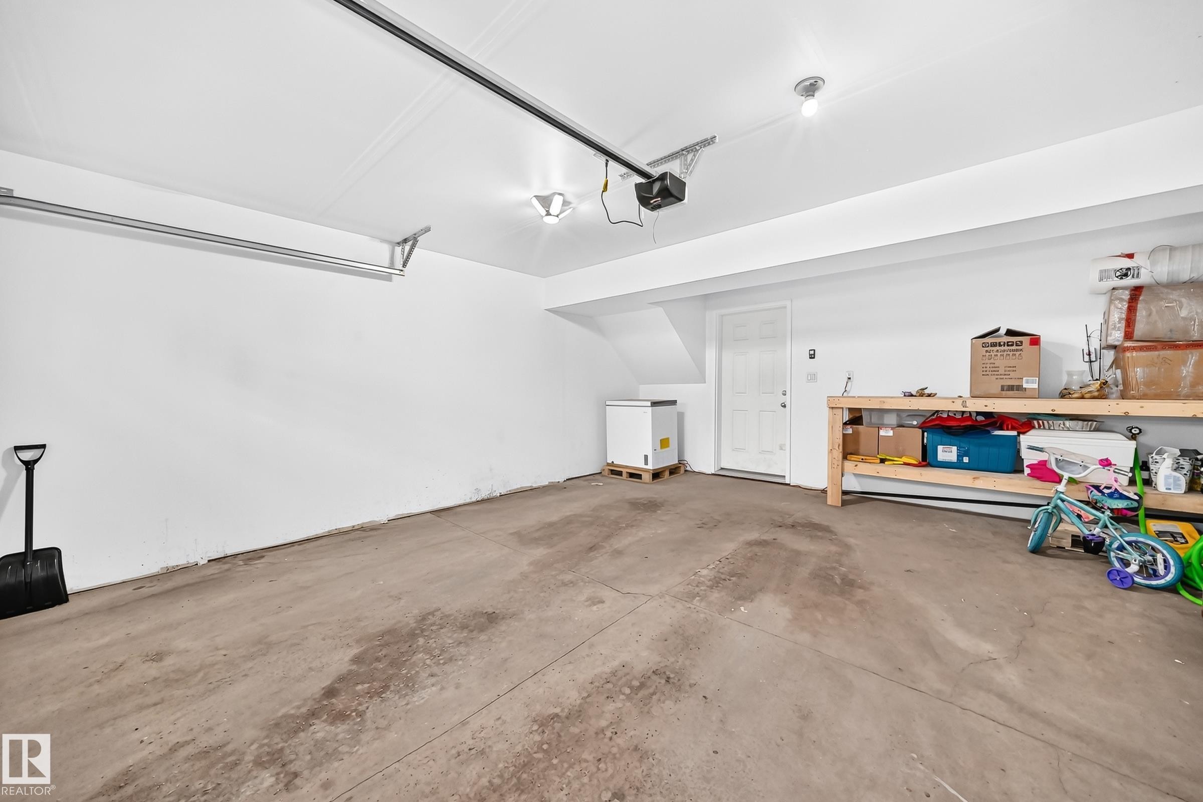 Spacious garage featuring a concrete floor, bright white walls, overhead lighting, and an automatic garage door opener - 415 Clareview Rd Nw Nw, Edmonton, AB - Indoor Photo Showing Garage