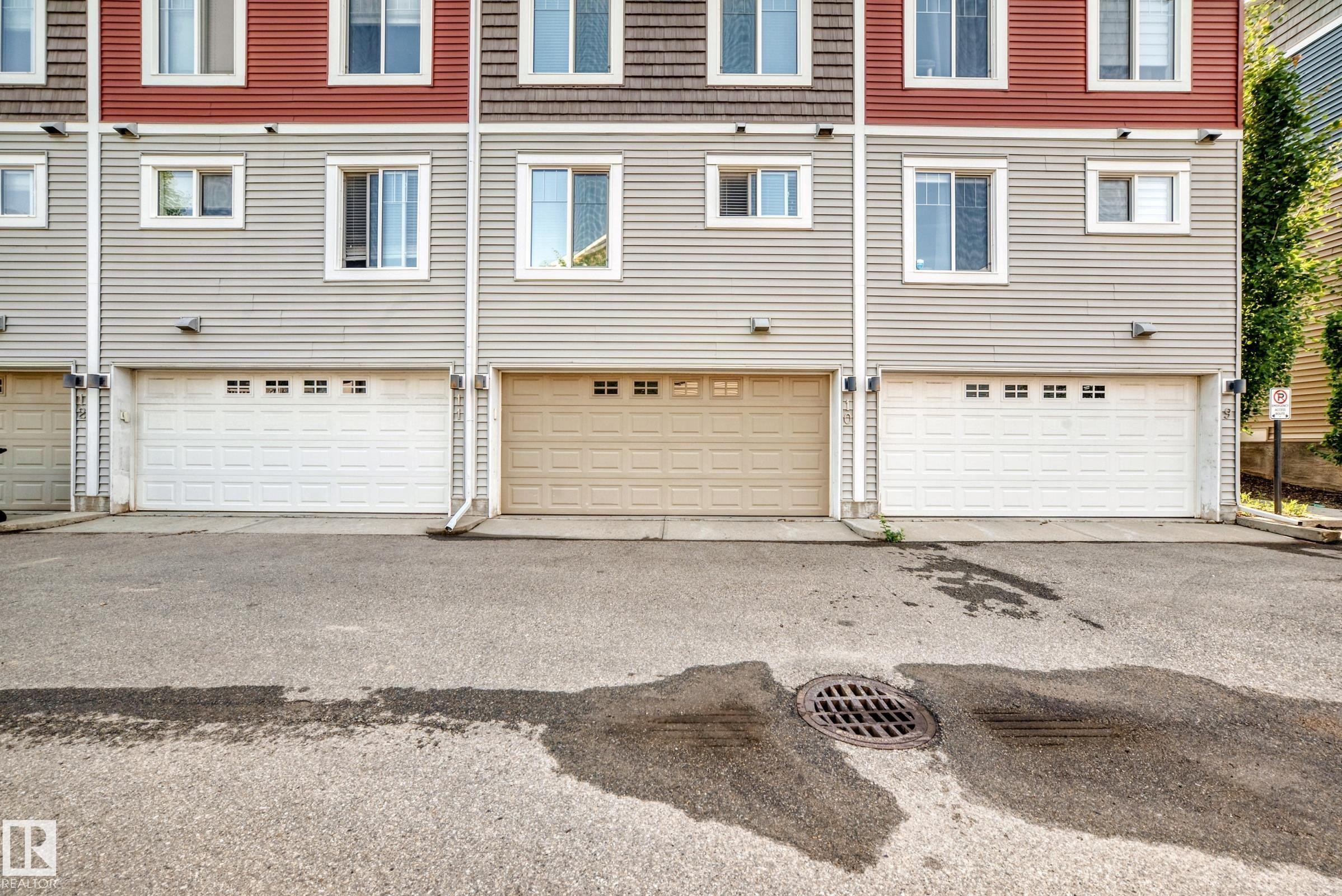 Multi-level townhome exterior featuring an attached garage with a panel door and upper window inserts - 415 Clareview Rd Nw Nw, Edmonton, AB - Outdoor