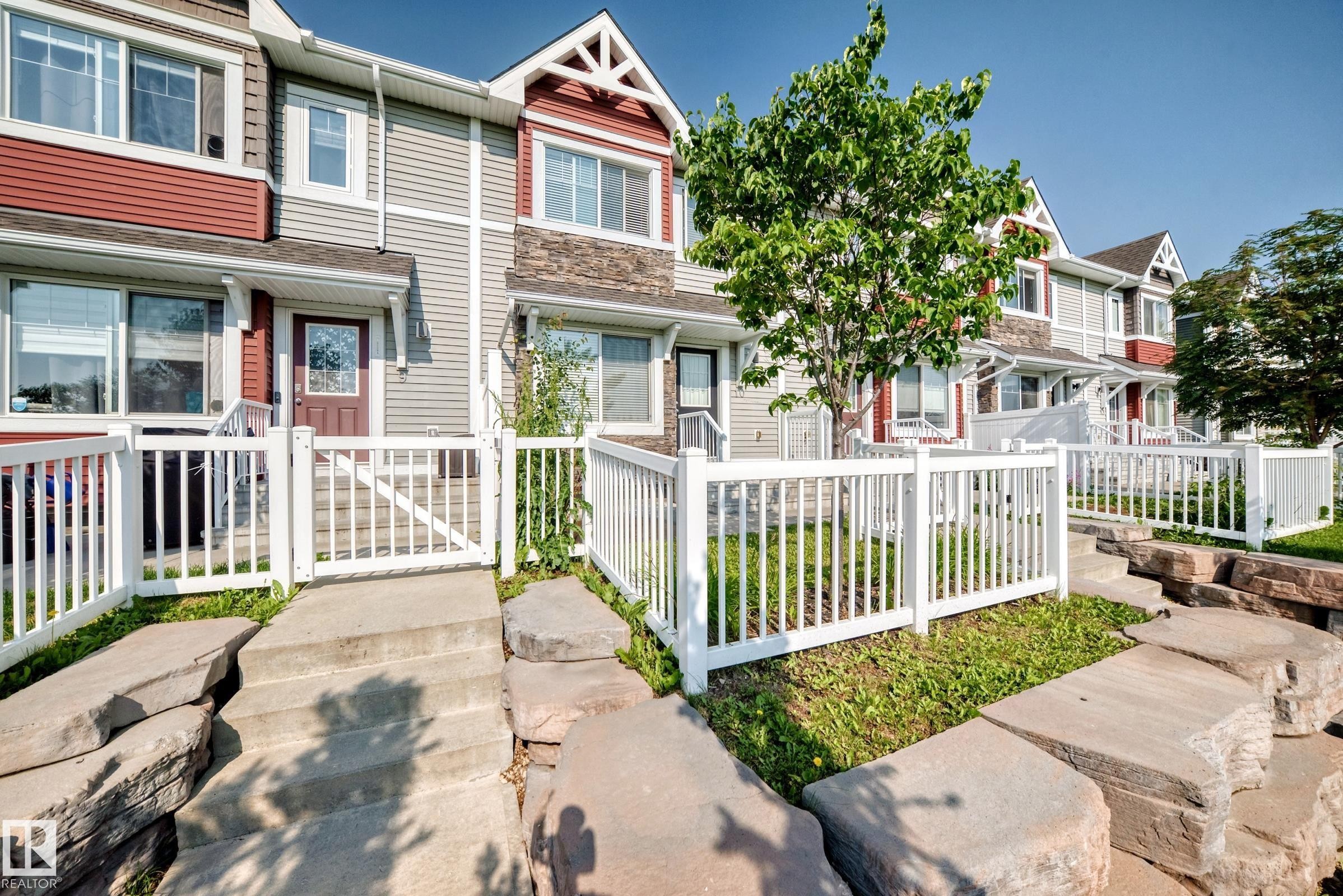 Multi-level townhouse exterior featuring durable siding, stone accents, and gabled rooflines - 415 Clareview Rd Nw Nw, Edmonton, AB - Outdoor With Facade