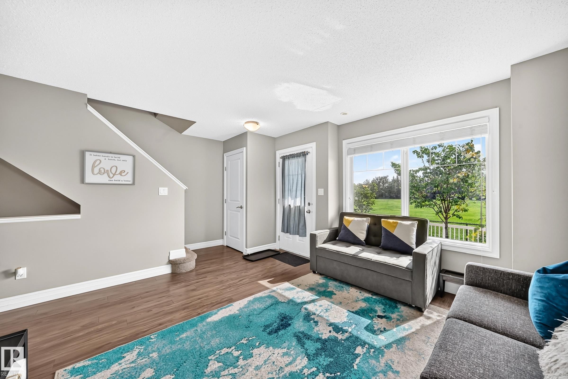 Spacious living area featuring wood-finish flooring, light gray wall paint, and white trim - 415 Clareview Rd Nw Nw, Edmonton, AB - Indoor Photo Showing Living Room