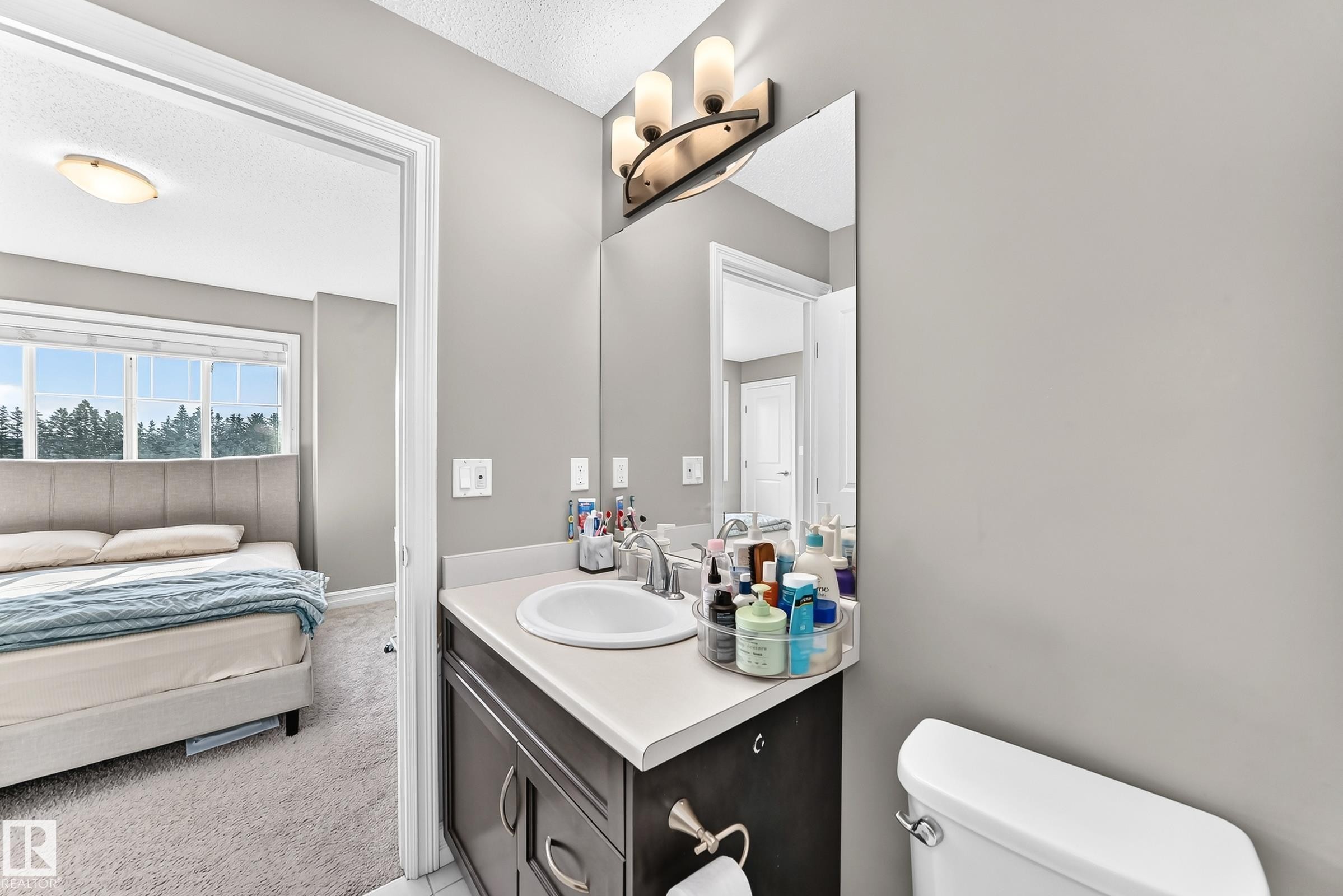 Bathroom vanity featuring a single sink, an integrated countertop, and a dark wood-finish cabinet with chrome hardware - 415 Clareview Rd Nw Nw, Edmonton, AB - Indoor Photo Showing Bathroom