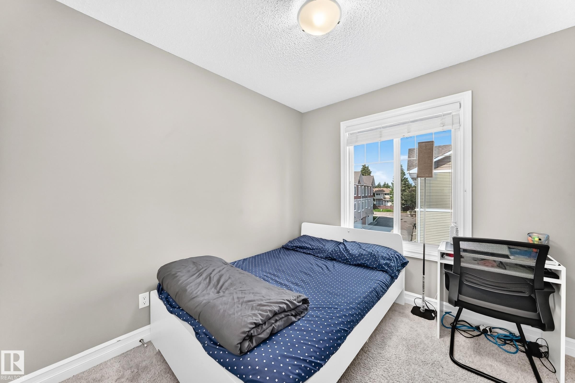 Light gray painted walls define this bright bedroom featuring a large window with white blinds - 415 Clareview Rd Nw Nw, Edmonton, AB - Indoor Photo Showing Bedroom
