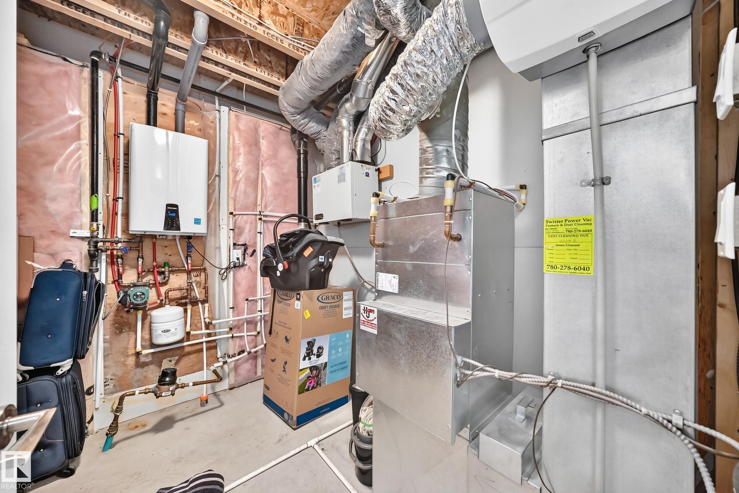 Utility room featuring a wall-mounted tankless water heater, extensive plumbing, exposed ductwork, and a furnace unit - 415 Clareview Rd Nw Nw, Edmonton, AB - Indoor Photo Showing Basement