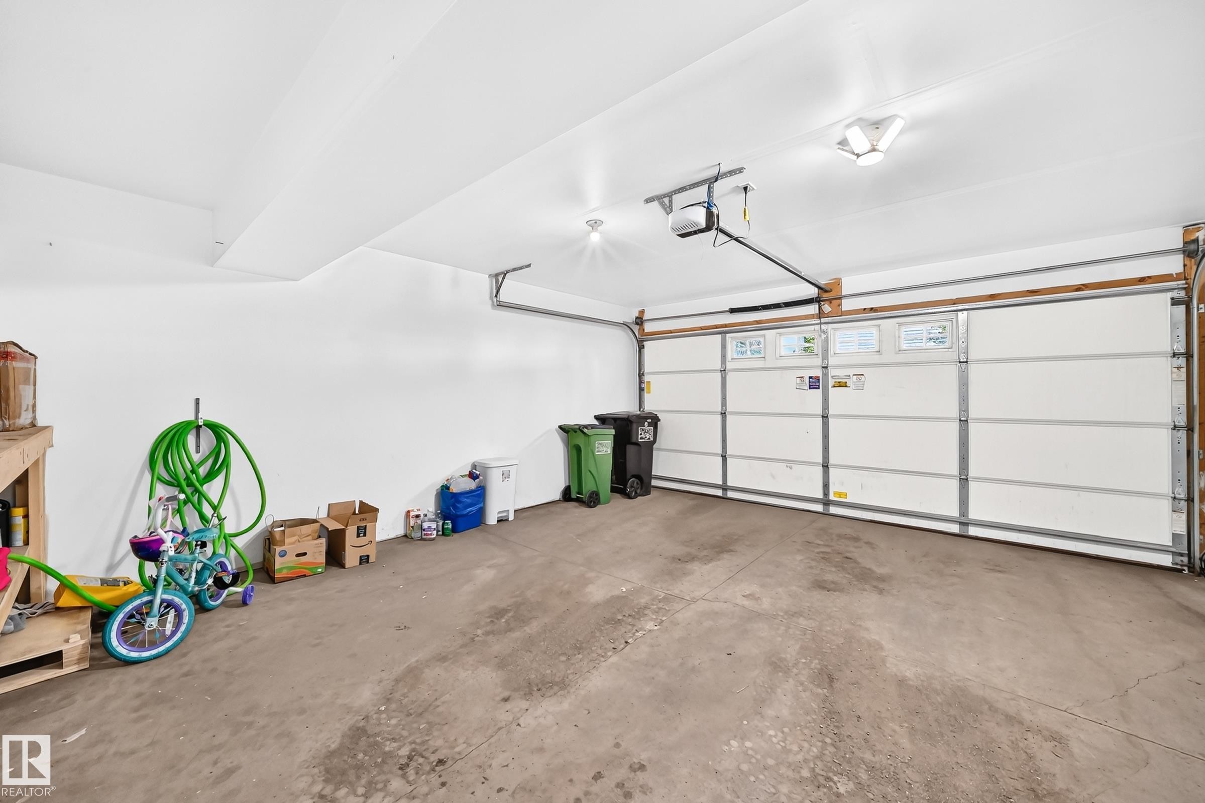 Spacious two-car garage featuring a concrete floor, white painted walls, and an automatic overhead door opener - 415 Clareview Rd Nw Nw, Edmonton, AB - Indoor Photo Showing Garage