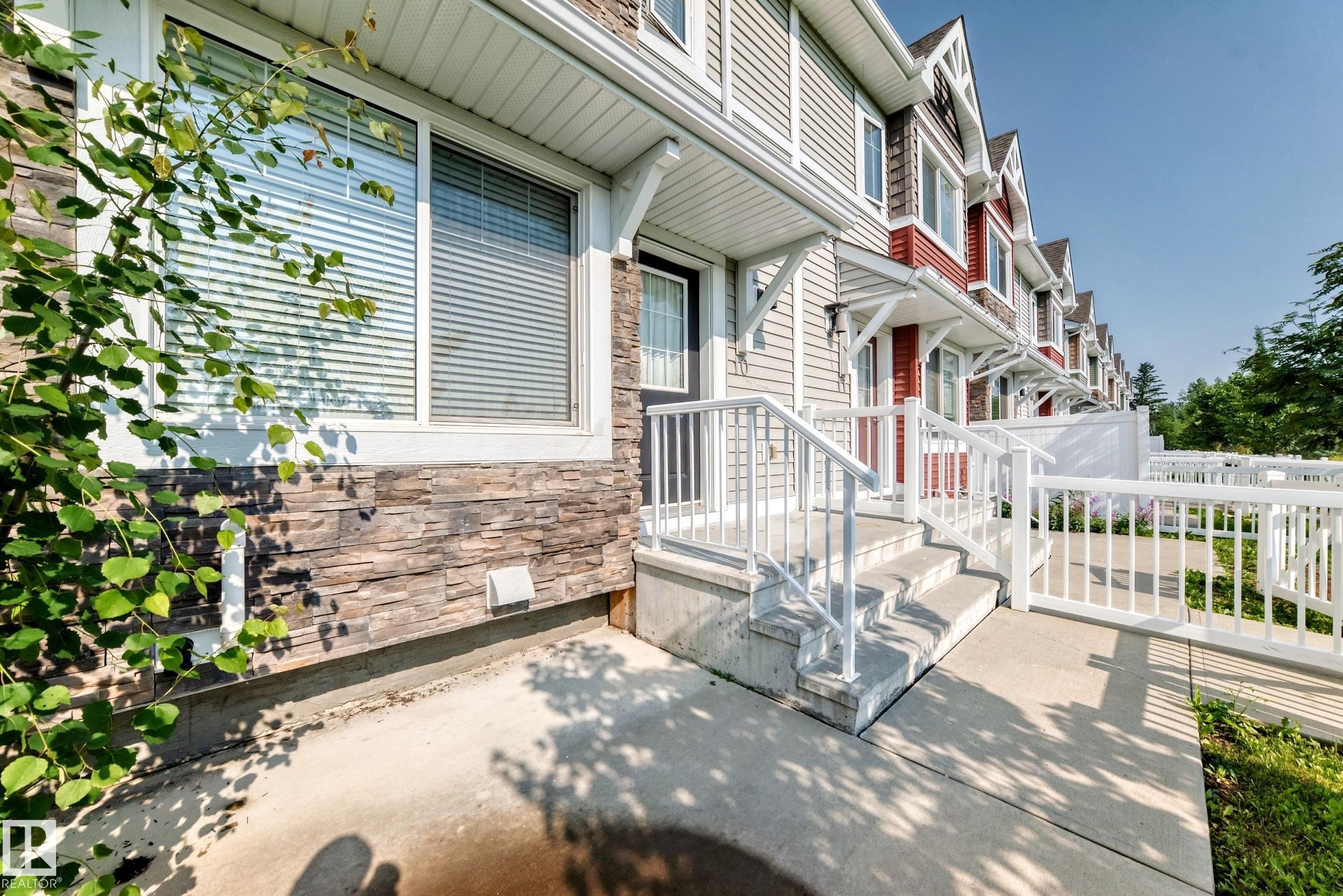 Exterior featuring stone veneer and horizontal siding, a concrete pathway, white railings, and a covered entryway - 415 Clareview Rd Nw Nw, Edmonton, AB - Outdoor