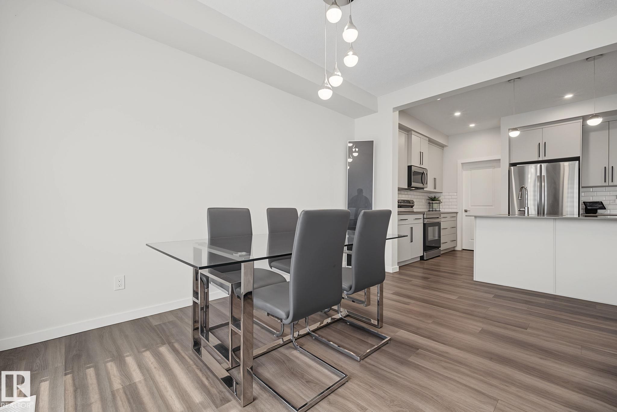 Open-concept living space featuring wood-finish flooring, white walls, and recessed lighting - 432 Roberts Crescent, Leduc, AB