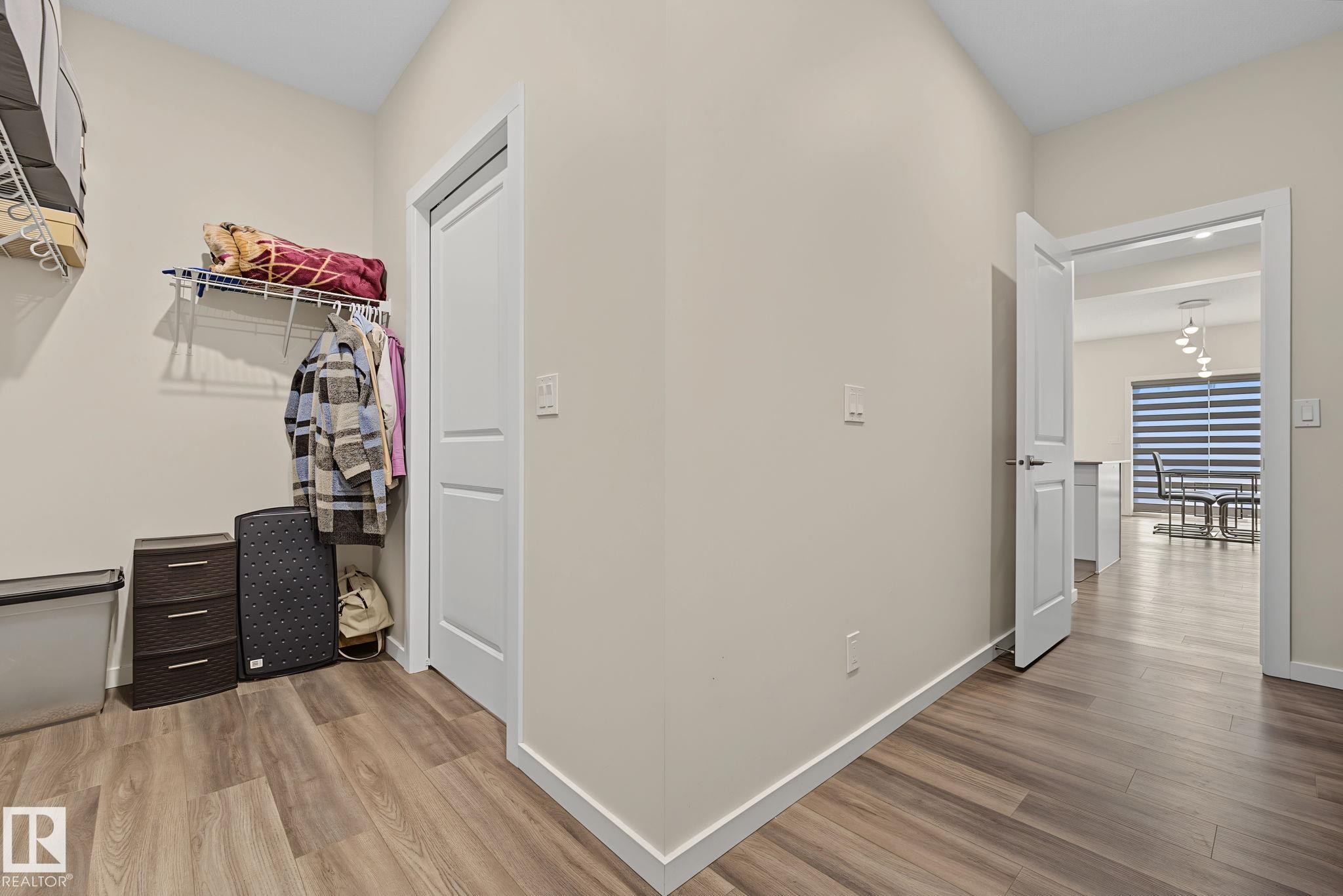 Hallway featuring wood-finish flooring, light neutral paint, and white baseboards - 432 Roberts Crescent, Leduc, AB