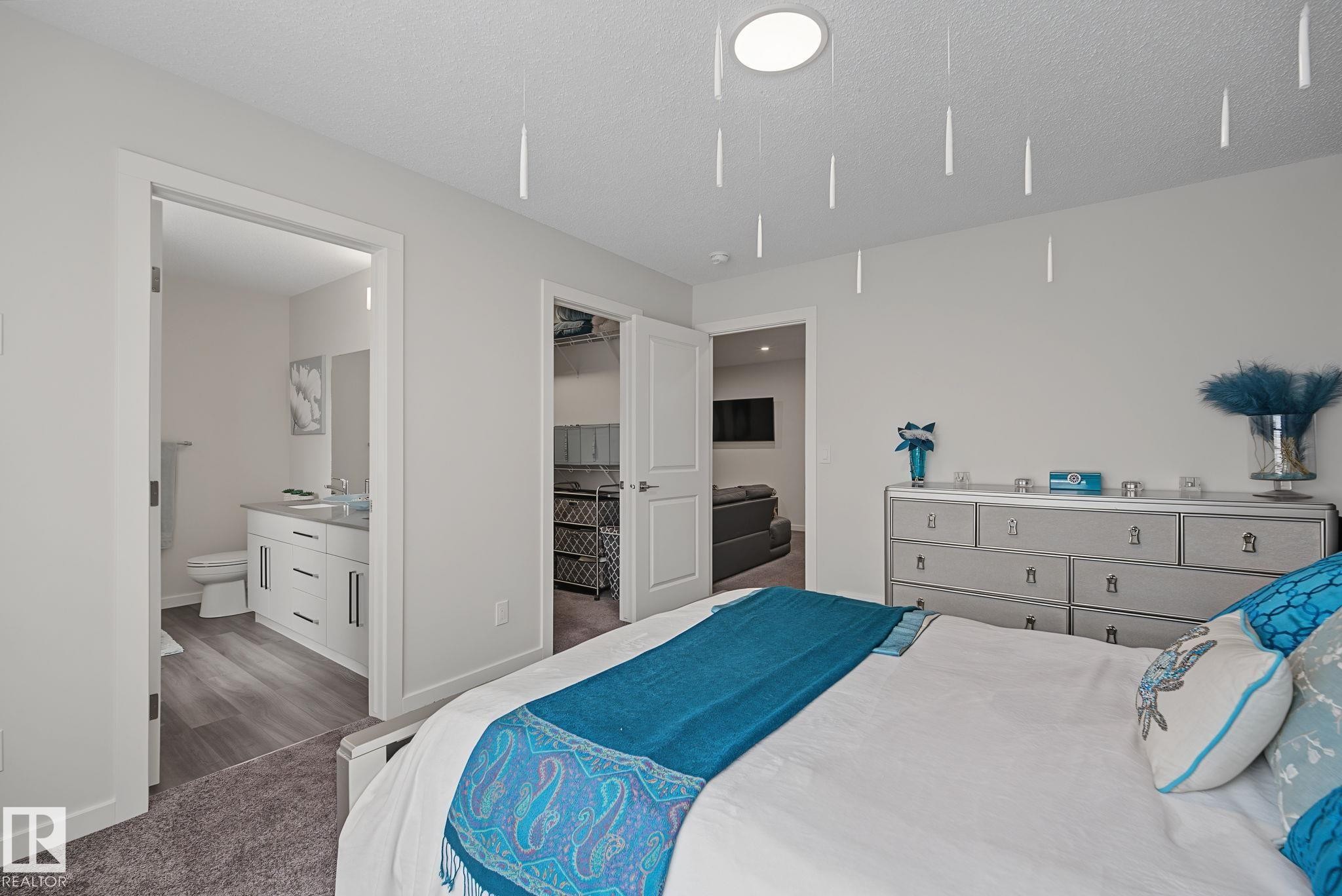 Light-filled bedroom featuring a recessed ceiling light, soft gray carpeting, and a built-in dresser with multiple drawers - 432 Roberts Crescent, Leduc, AB