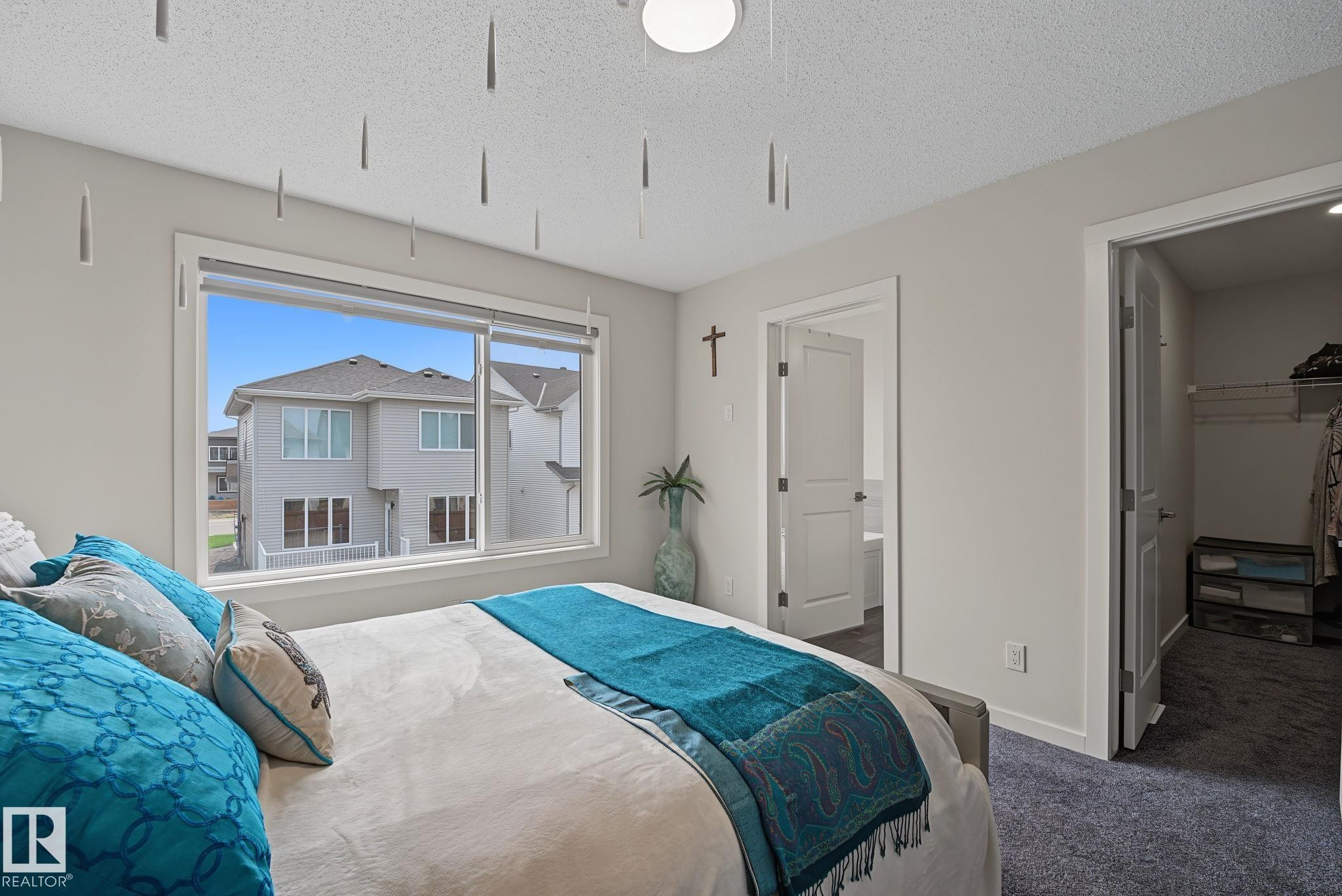 Spacious room featuring a large window with white trim, soft gray wall paint, and plush carpet flooring - 432 Roberts Crescent, Leduc, AB