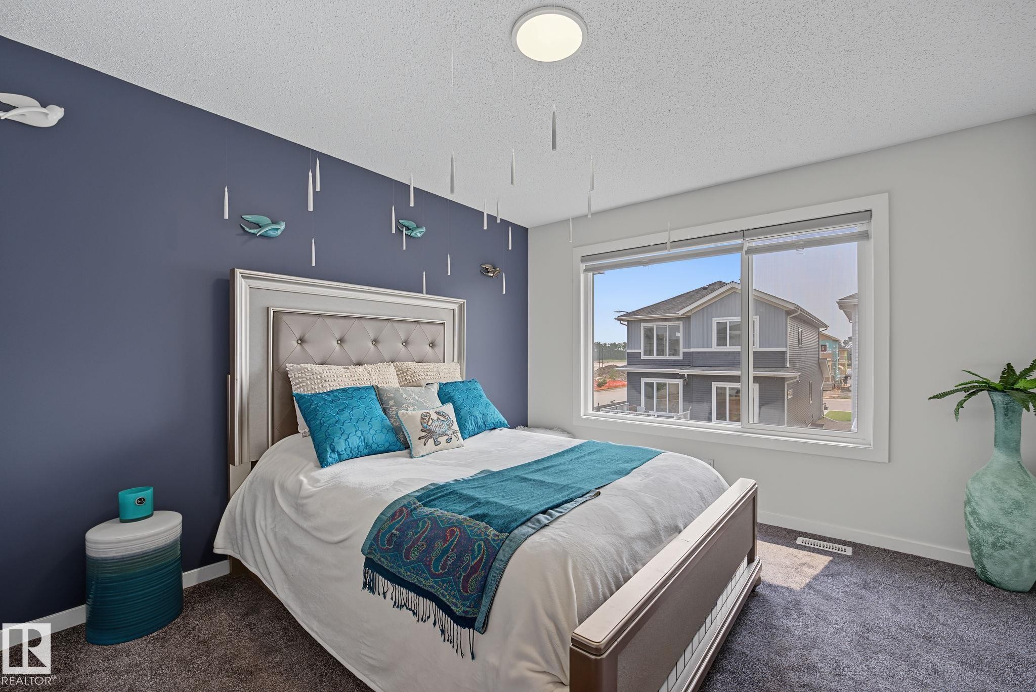 Bedroom featuring a large picture window, a textured carpet, and a flush-mount ceiling light - 432 Roberts Crescent, Leduc, AB