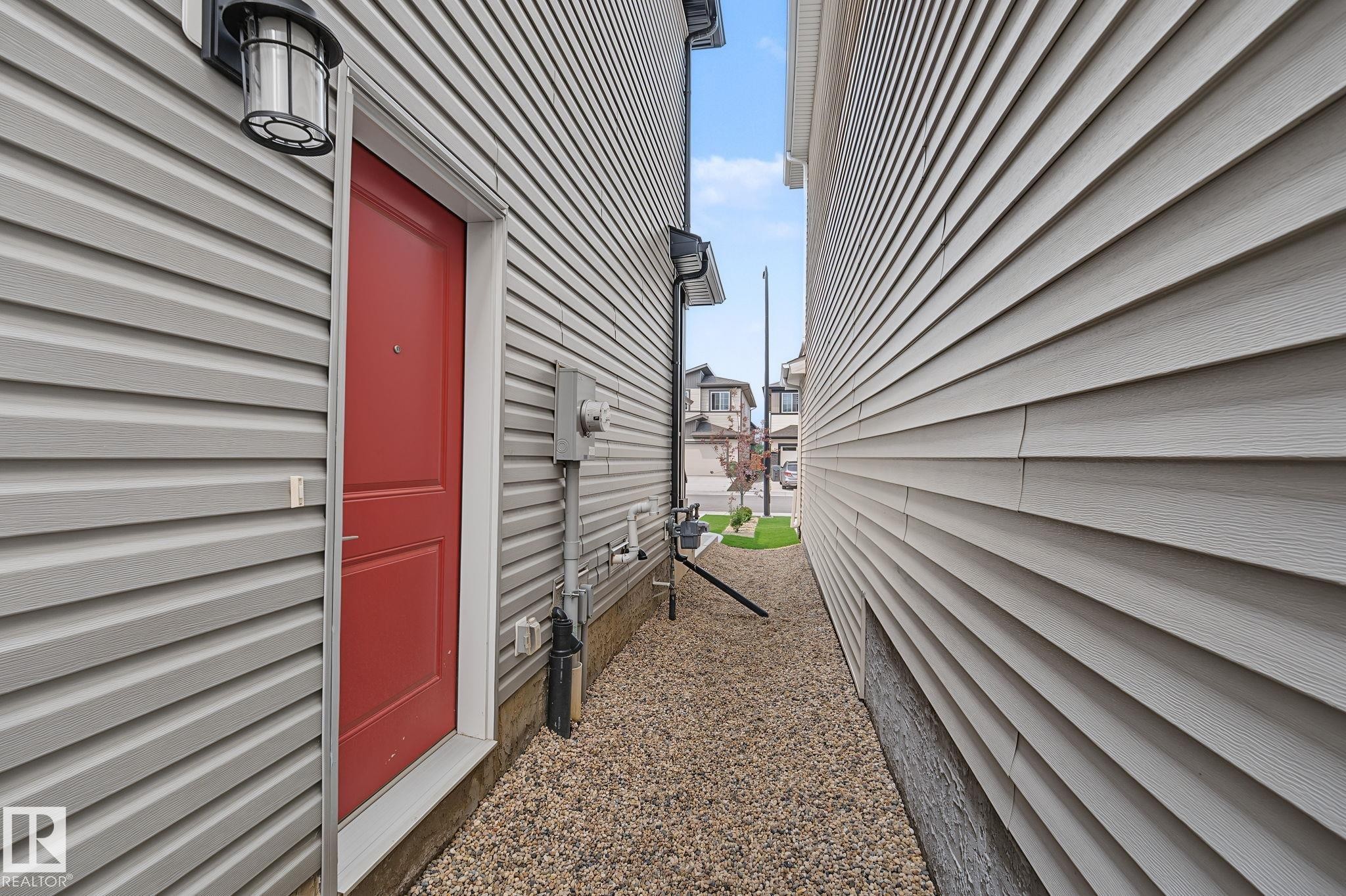Red entry door with an overhead lantern fixture - 432 Roberts Crescent, Leduc, AB