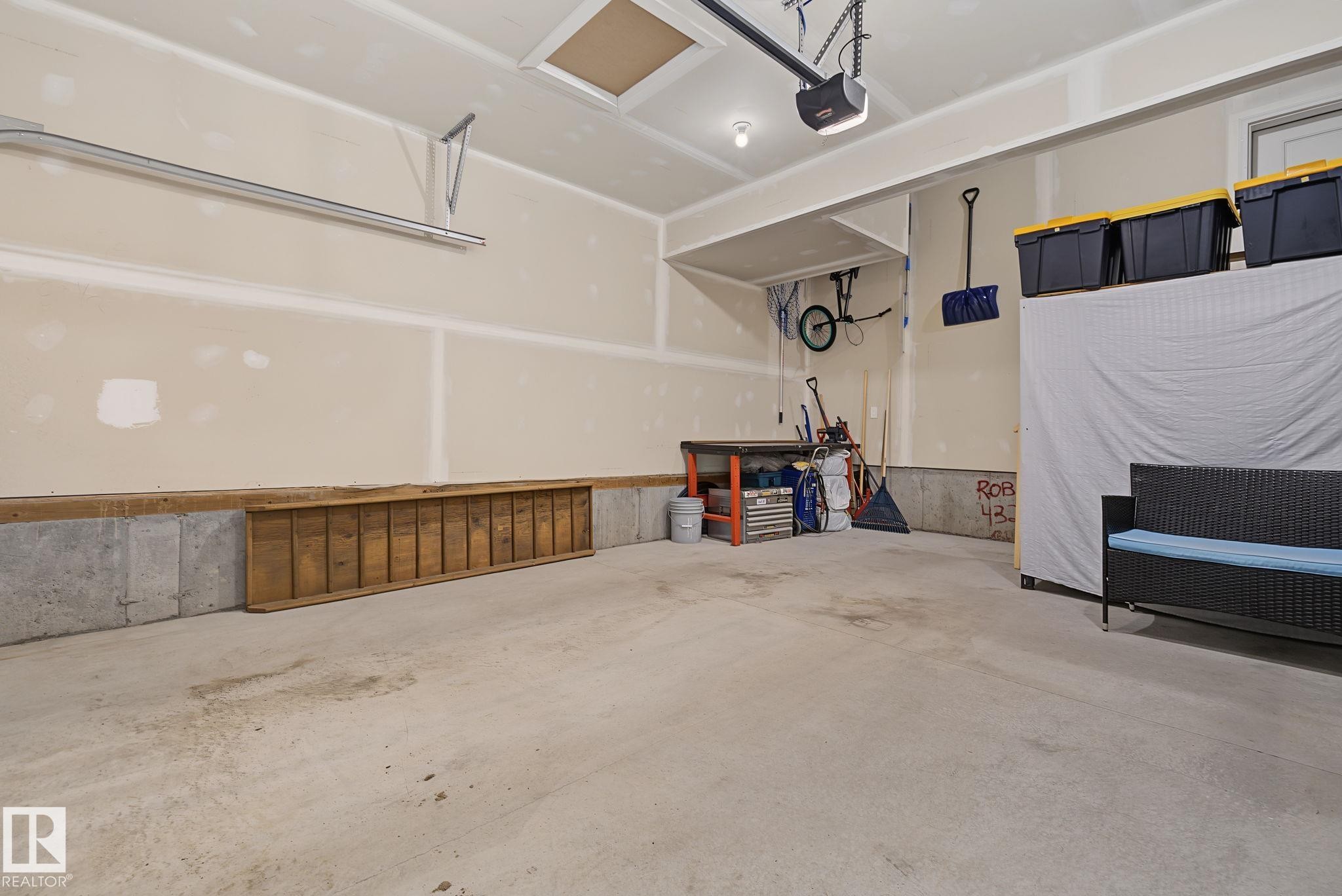 Spacious garage featuring a concrete floor, concrete foundation perimeter, and an automatic garage door opener - 432 Roberts Crescent, Leduc, AB
