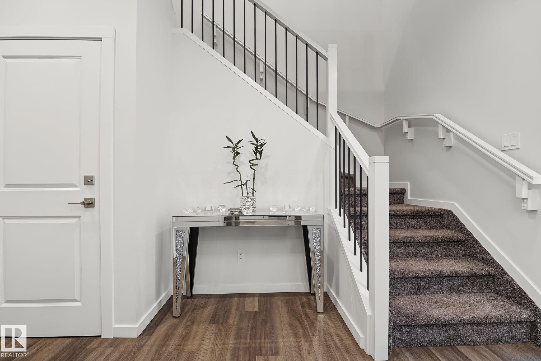 Staircase with carpeted treads and white risers, featuring dark metal balusters and a white handrail - 432 Roberts Crescent, Leduc, AB