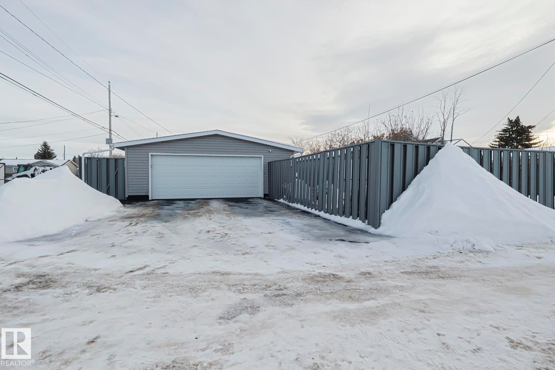 Detached garage featuring horizontal siding and a white sectional overhead door - 13304 70 Street, Edmonton, AB