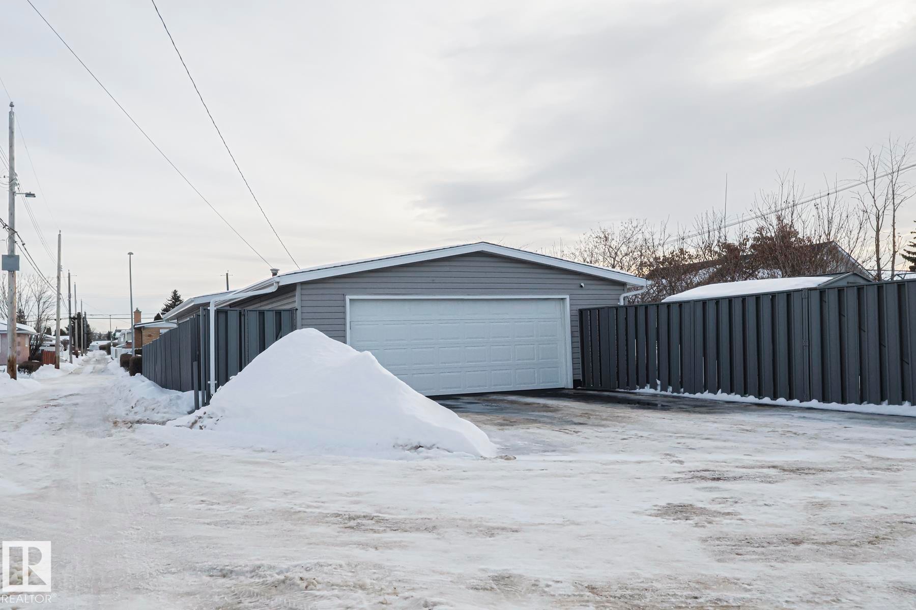 Detached garage featuring light gray siding and a white overhead door - 13304 70 Street, Edmonton, AB