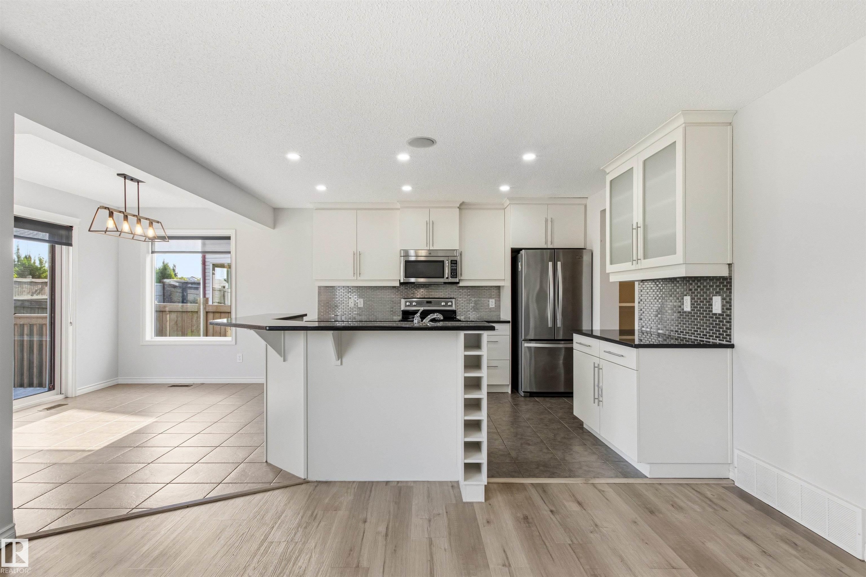 Modern kitchen featuring white cabinetry, stainless steel appliances, dark countertops, and a patterned tile backsplash - 3214 22A Avenue Nw, Edmonton, AB - Indoor Photo Showing Kitchen With Stainless Steel Kitchen With Upgraded Kitchen