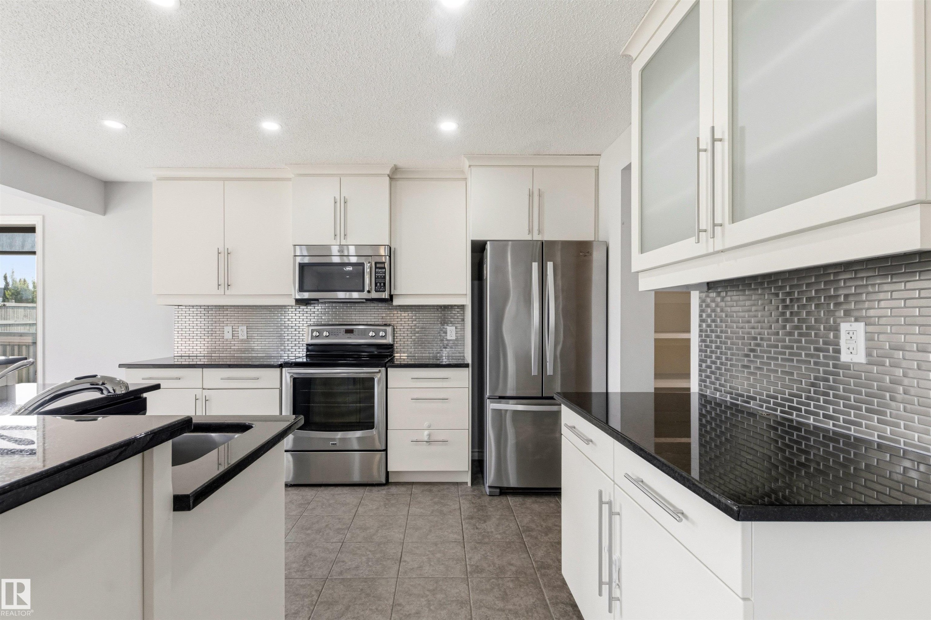 Modern kitchen featuring white cabinetry, dark countertops, and stainless steel appliances - 3214 22A Avenue Nw, Edmonton, AB - Indoor Photo Showing Kitchen With Stainless Steel Kitchen With Upgraded Kitchen