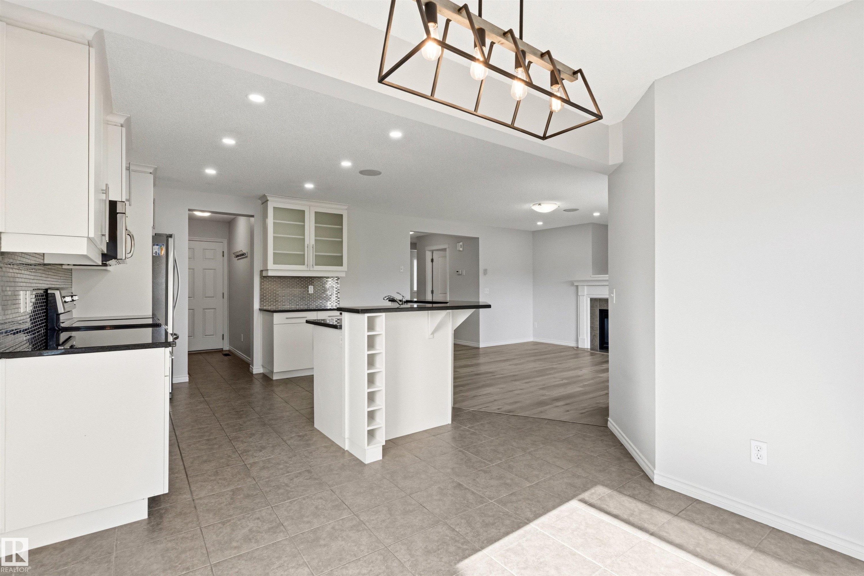 Kitchen featuring white cabinetry, black countertops, stainless steel appliances, and a tiled backsplash - 3214 22A Avenue Nw, Edmonton, AB - Indoor Photo Showing Kitchen