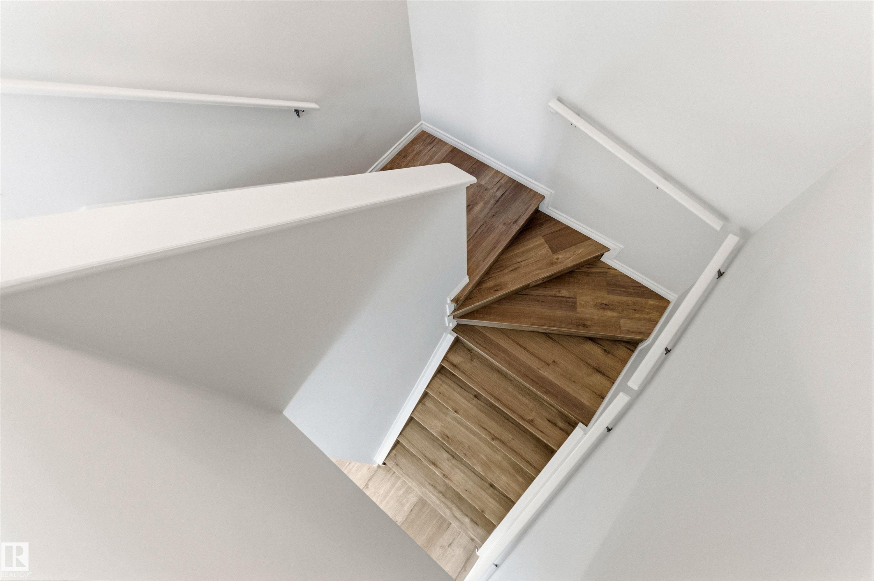 Spiral staircase featuring wood-finish treads, white risers, and white handrails - 3214 22A Avenue Nw, Edmonton, AB - Indoor Photo Showing Other Room