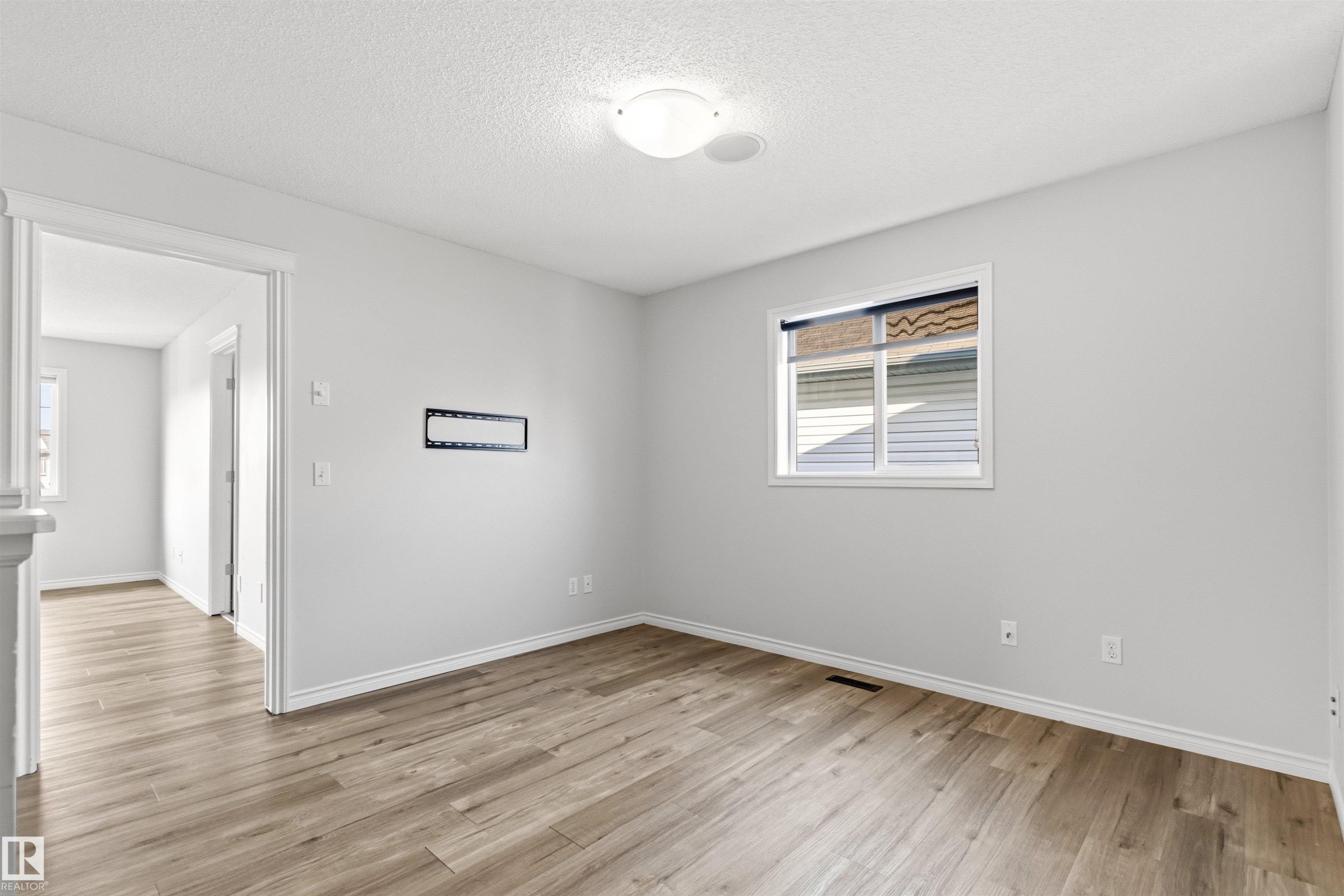 Light-filled room featuring wood-finish flooring, a white trim package, and a flush-mount ceiling light - 3214 22A Avenue Nw, Edmonton, AB - Indoor Photo Showing Other Room