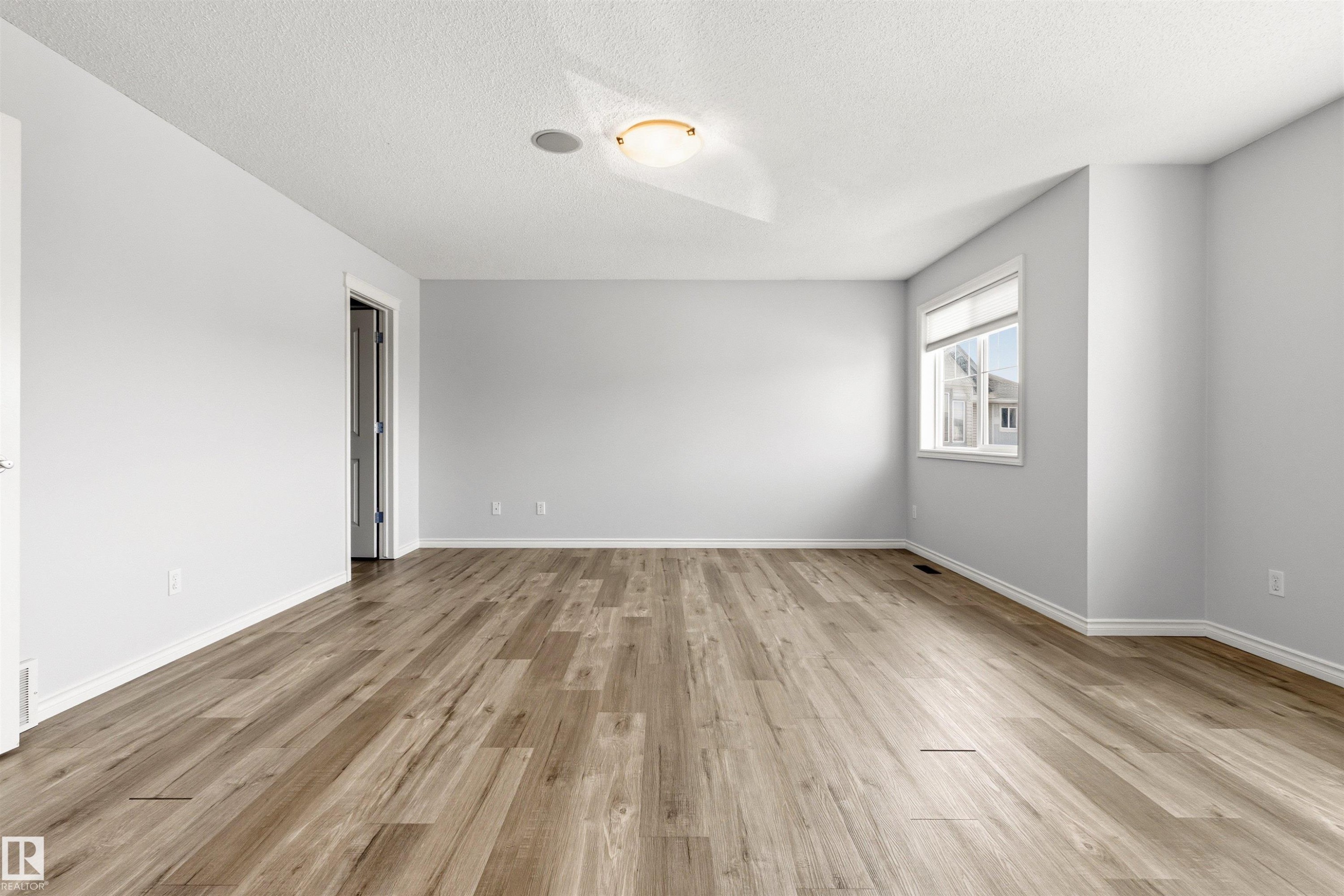 Spacious room featuring wood-finish flooring and neutral wall tones - 3214 22A Avenue Nw, Edmonton, AB - Indoor Photo Showing Other Room