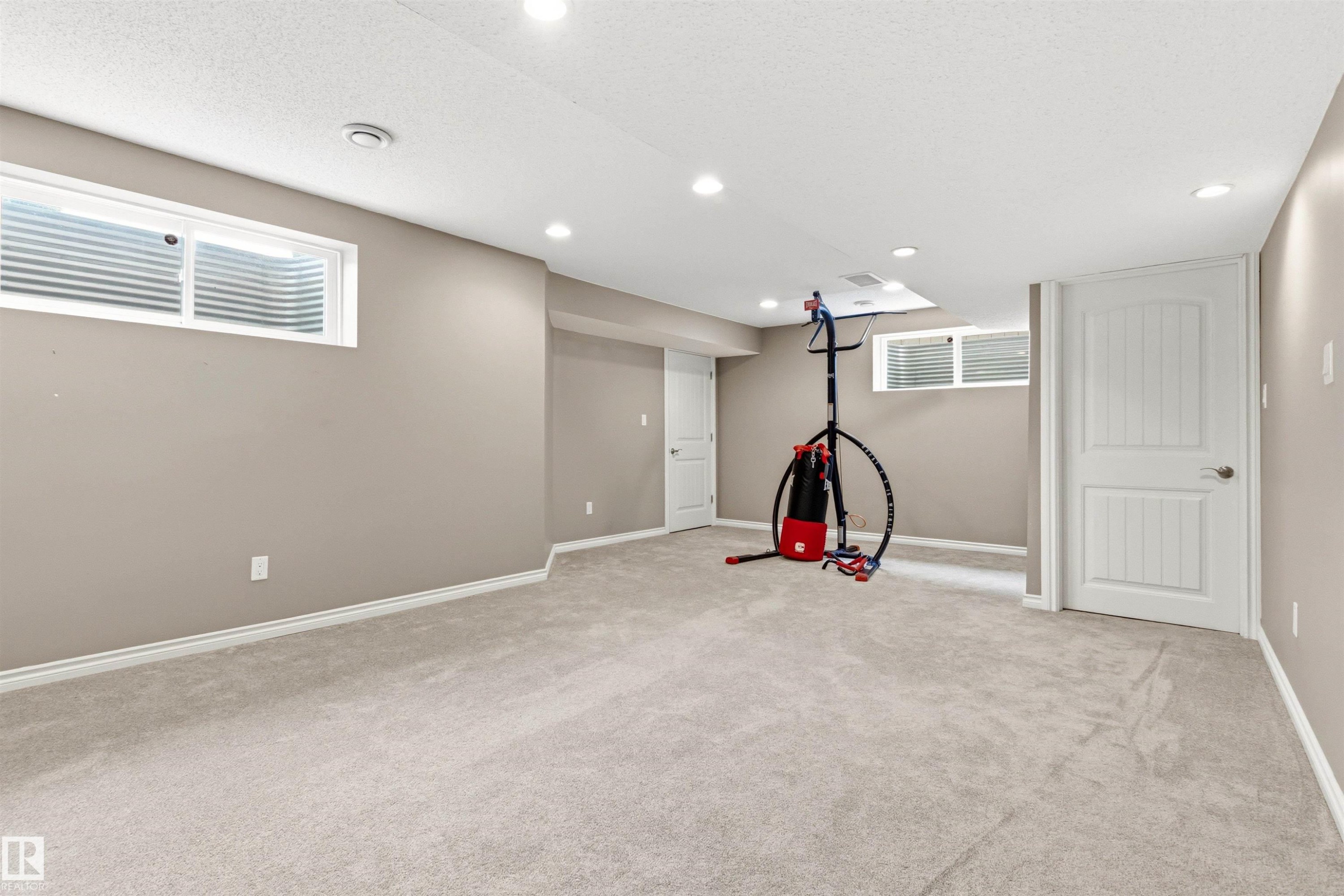 Finished lower level with neutral carpeting, recessed lighting, and egress windows - 3214 22A Avenue Nw, Edmonton, AB - Indoor Photo Showing Basement