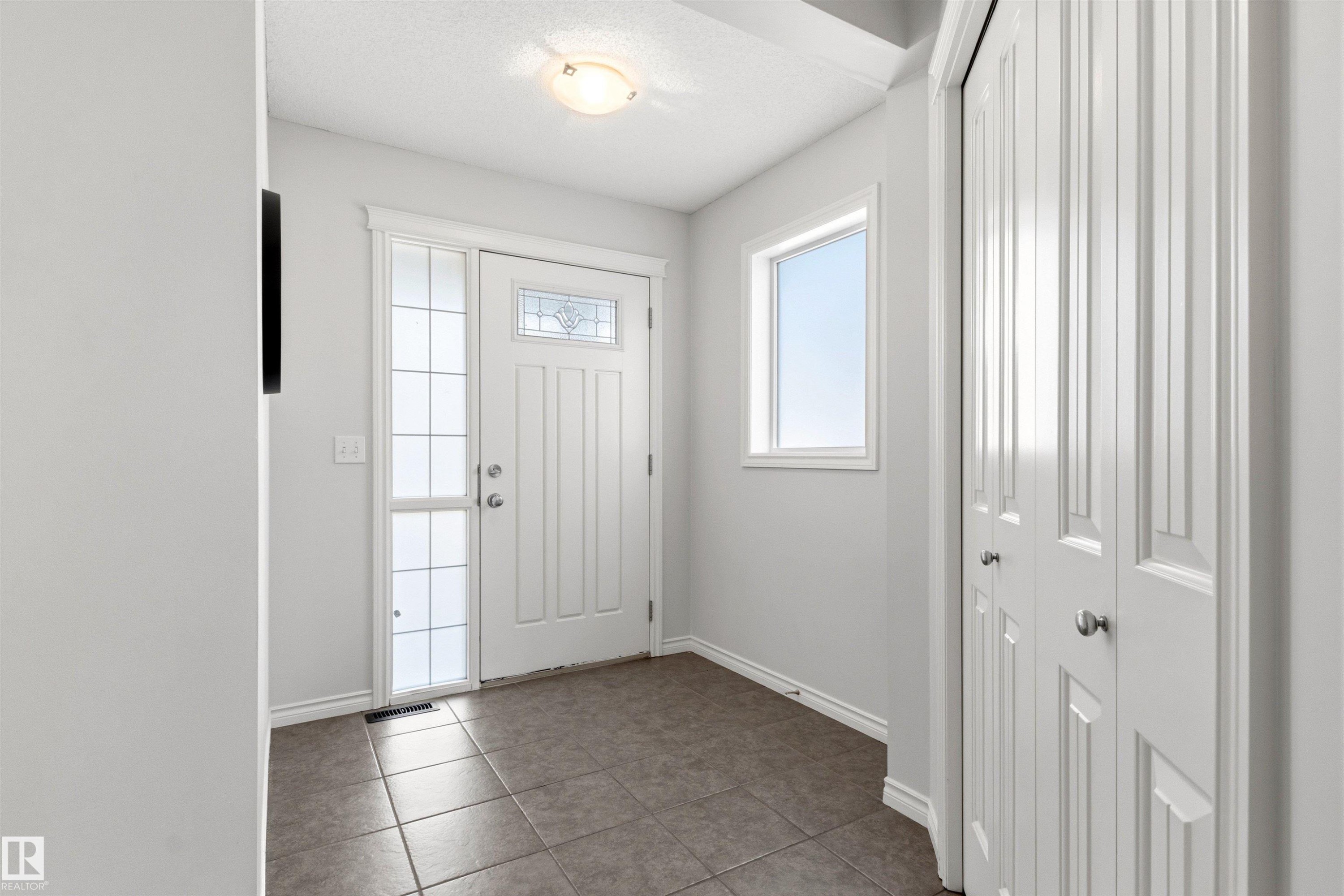 Entryway featuring a paneled door with decorative glass, a sidelight, and a window - 3214 22A Avenue Nw, Edmonton, AB - Indoor Photo Showing Other Room
