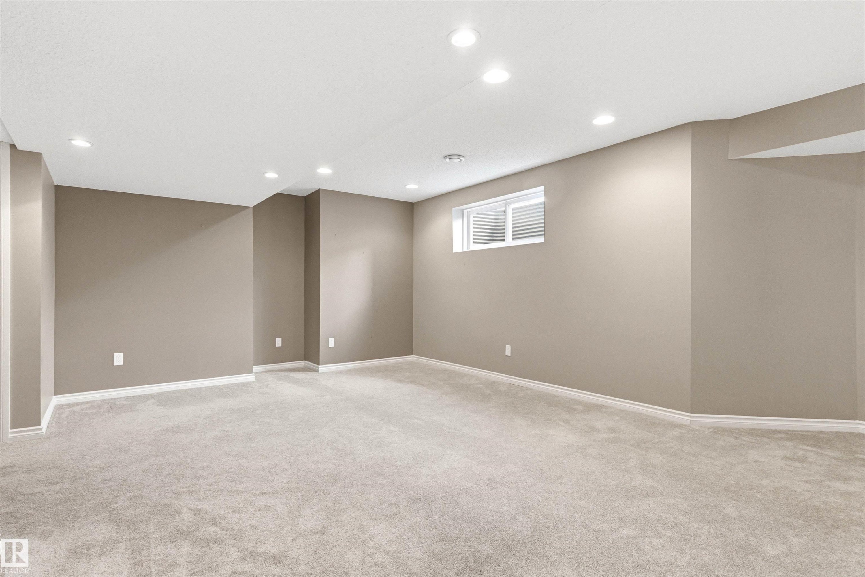 Spacious room featuring light gray carpeting, recessed ceiling lighting, a single window, and neutral-toned walls with white baseboards - 3214 22A Avenue Nw, Edmonton, AB - Indoor