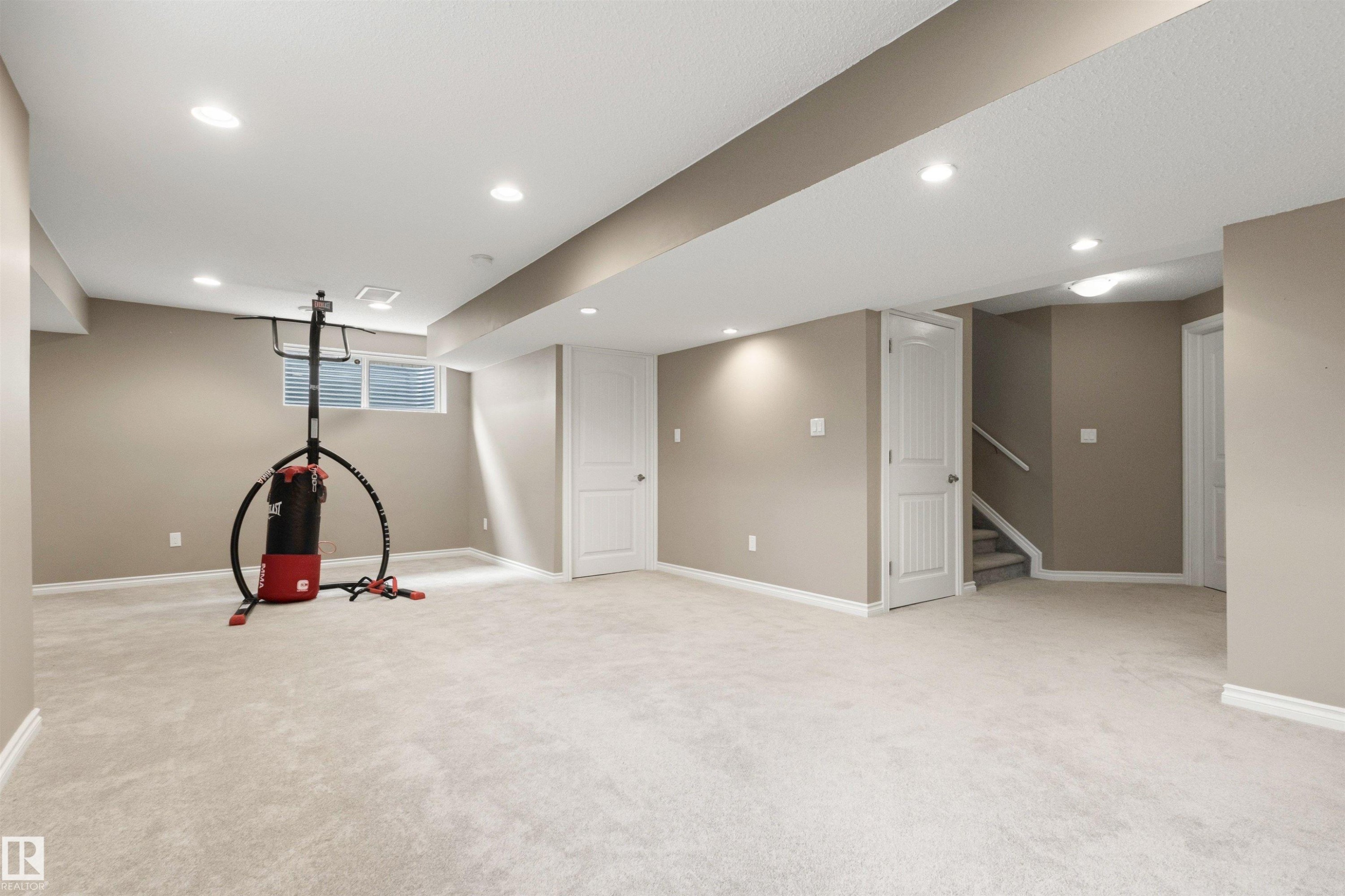 Spacious interior room featuring light-colored carpeting, neutral wall tones, white trim, recessed lighting, and a visible window - 3214 22A Avenue Nw, Edmonton, AB - Indoor