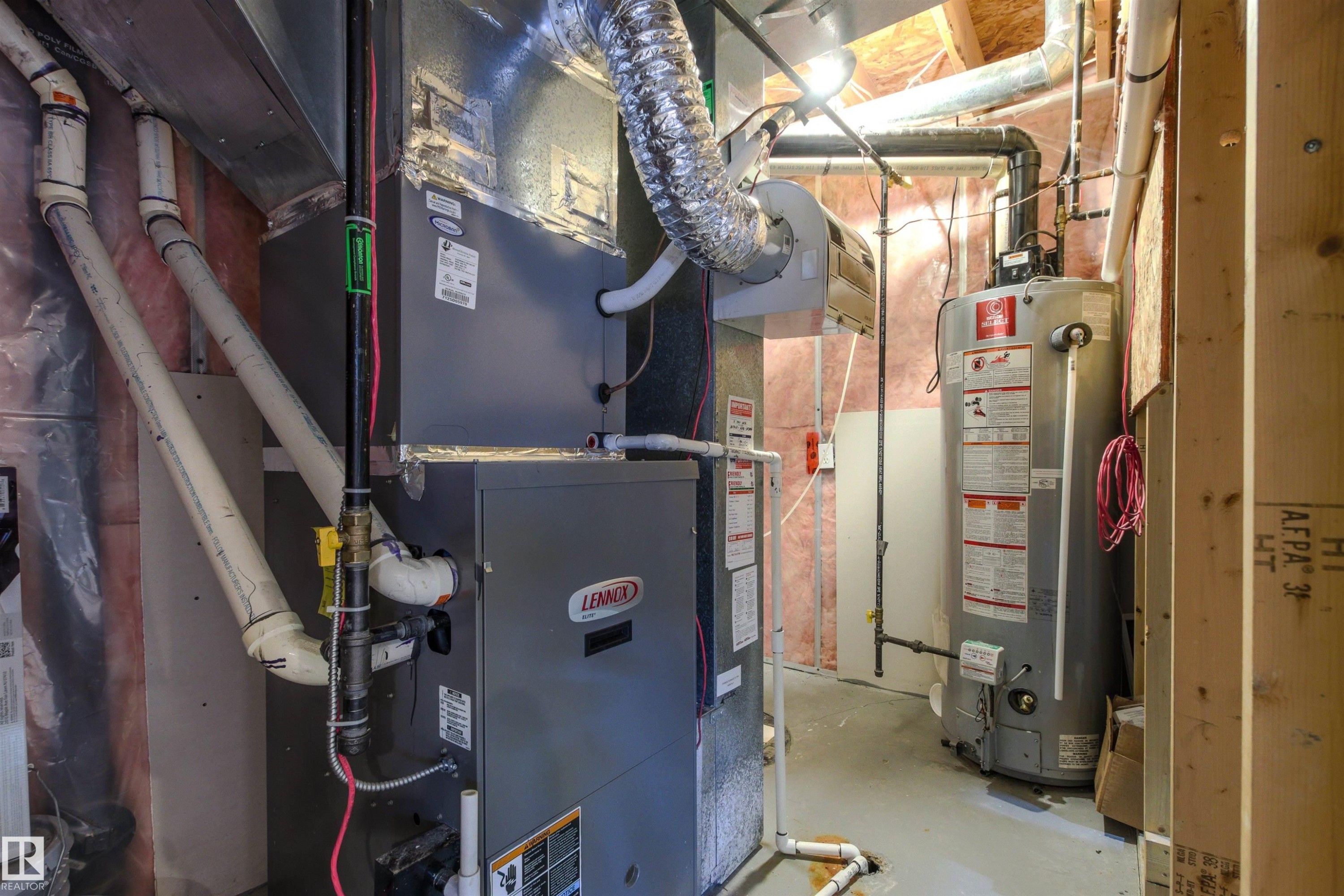 Dedicated utility space featuring a Lennox furnace, an attached water heater, extensive ductwork, and exposed insulation - 3214 22A Avenue Nw, Edmonton, AB - Indoor Photo Showing Basement