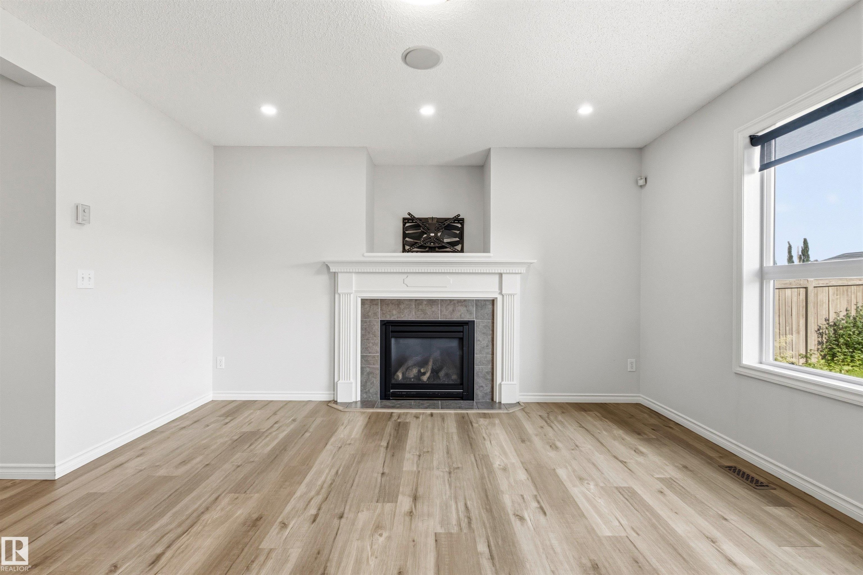 Living area featuring a fireplace with a white mantel and a tiled surround - 3214 22A Avenue Nw, Edmonton, AB - Indoor Photo Showing Living Room With Fireplace