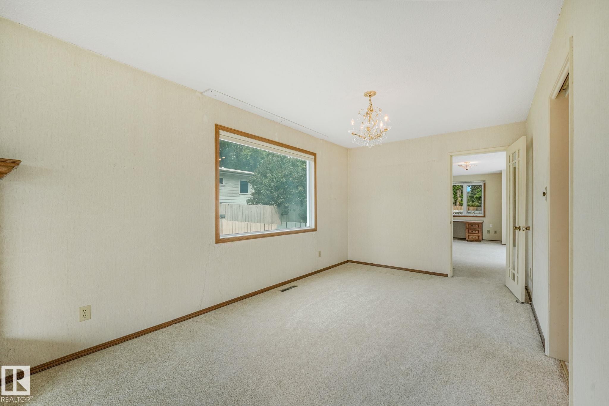 Carpeted room with a large window featuring wood trim - 13320 79 Avenue Nw, Edmonton, AB - Indoor Photo Showing Other Room