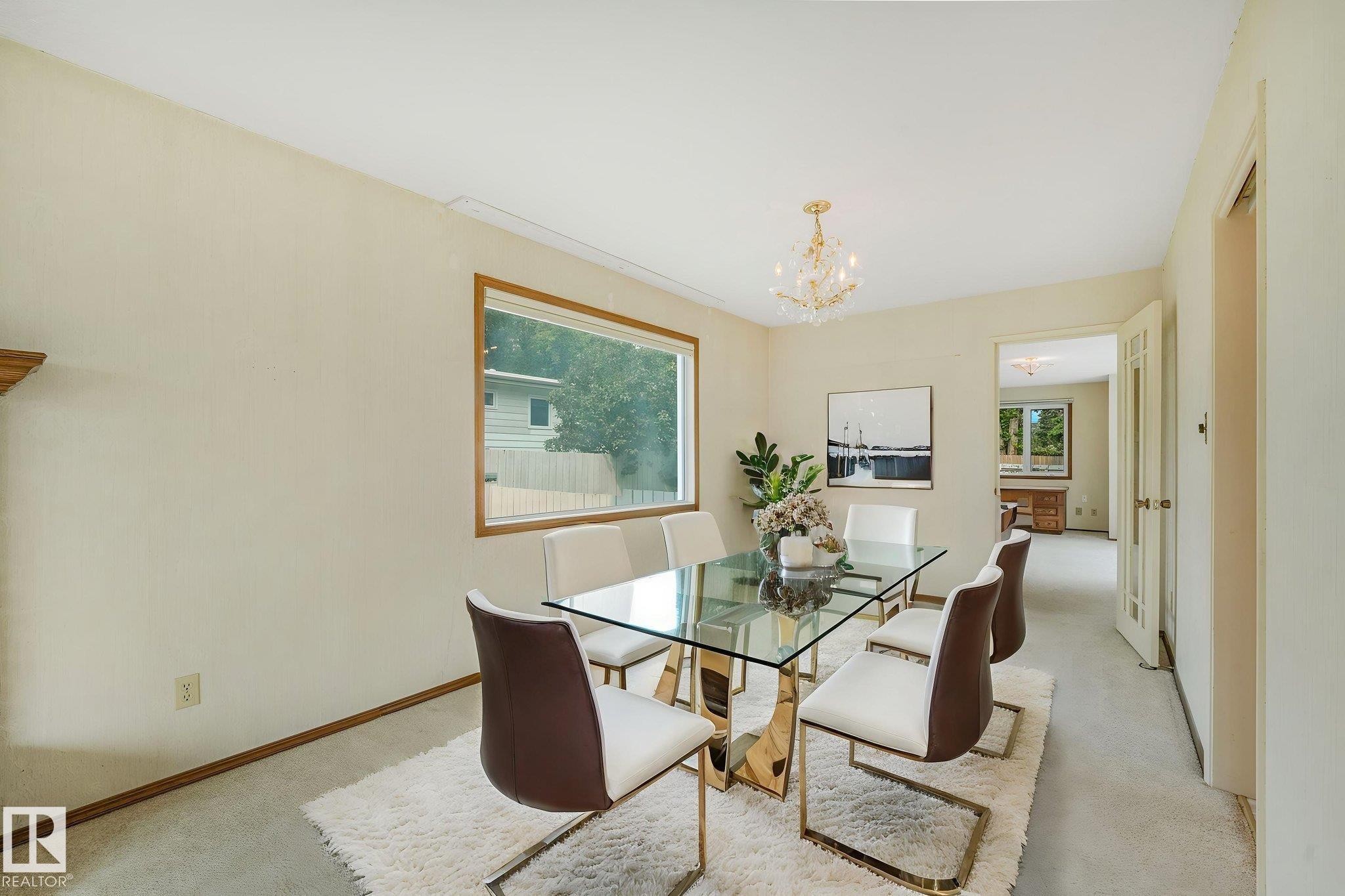 Formal dining space featuring a wood-trimmed window, a crystal chandelier, and neutral-toned carpeting - 13320 79 Avenue Nw, Edmonton, AB - Indoor Photo Showing Dining Room