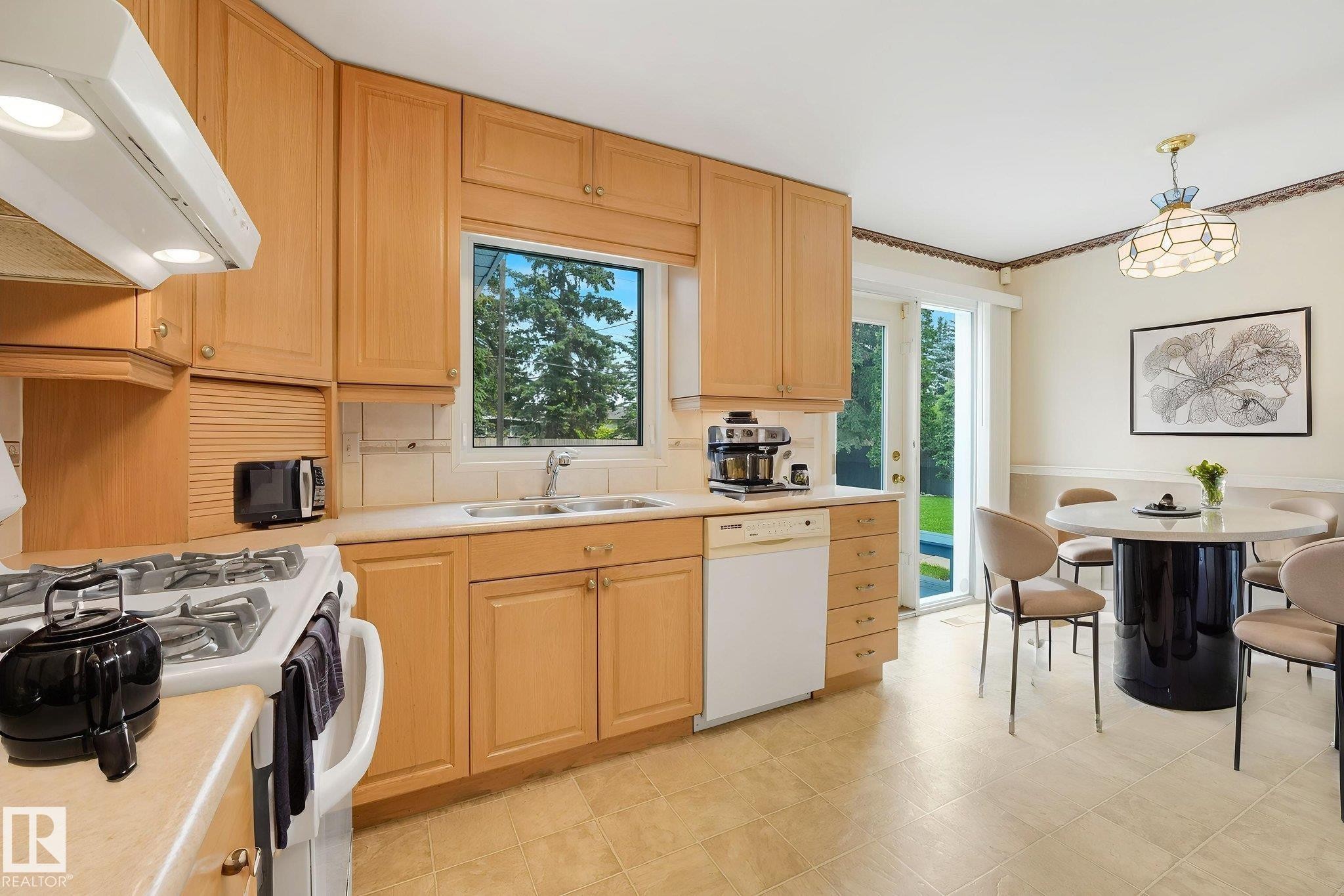 Bright kitchen featuring wood cabinetry, white appliances, and a window above the sink - 13320 79 Avenue Nw, Edmonton, AB - Indoor Photo Showing Kitchen With Double Sink