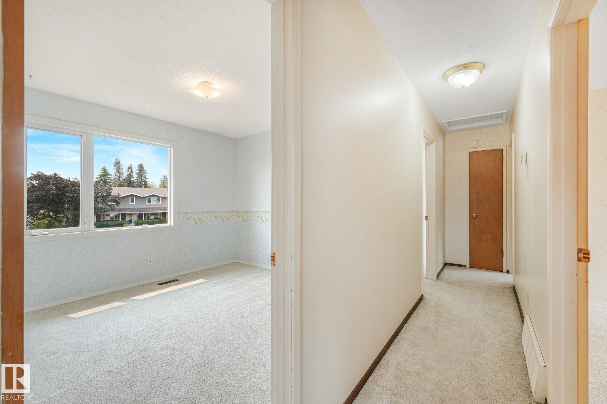 Bright interior room featuring a large window, light-colored carpeting, white walls, and a ceiling-mounted light fixture - 13320 79 Avenue Nw, Edmonton, AB - Indoor Photo Showing Other Room