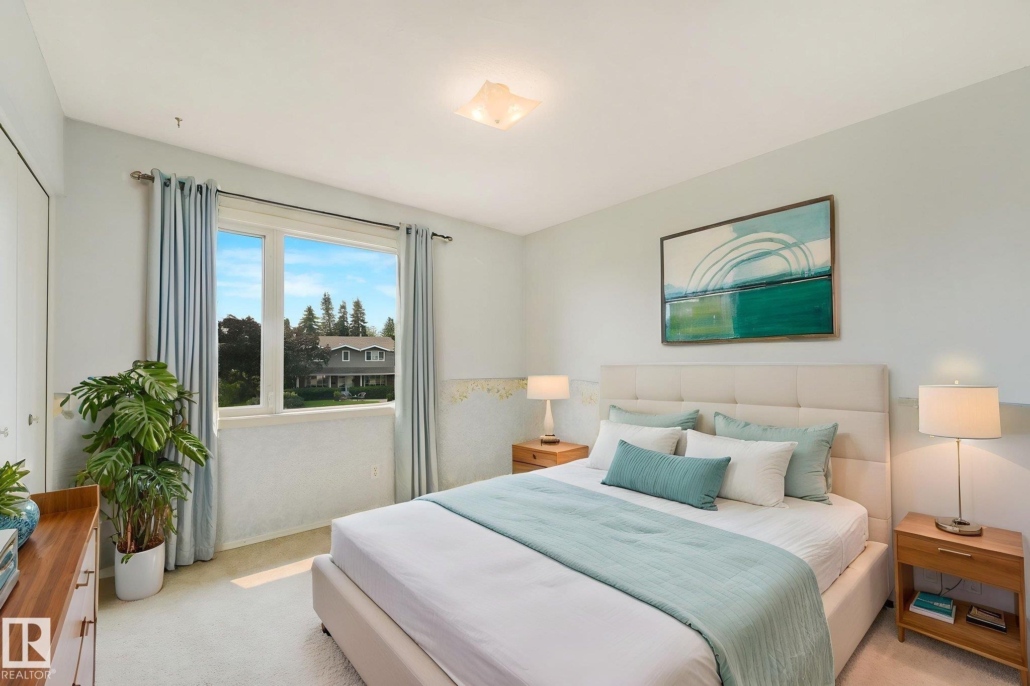 Bedroom featuring a large window, soft neutral wall colors, light-colored carpet flooring, a flush-mount ceiling light fixture, and a built-in closet with bifold doors - 13320 79 Avenue Nw, Edmonton, AB - Indoor Photo Showing Bedroom