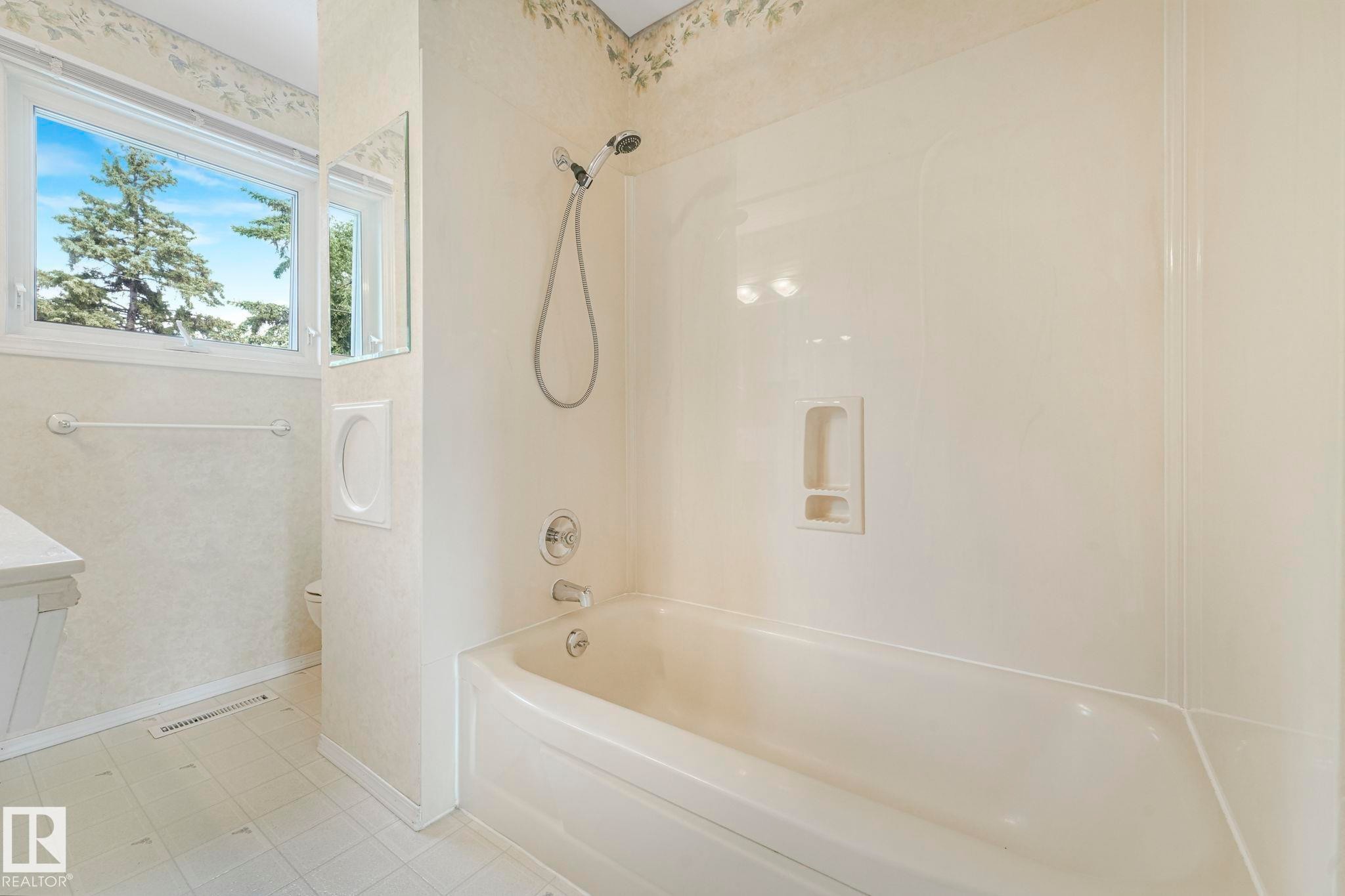 Bathroom featuring a tub/shower combination with a hand-held shower head, chrome fixtures, and a built-in soap dish - 13320 79 Avenue Nw, Edmonton, AB - Indoor Photo Showing Bathroom