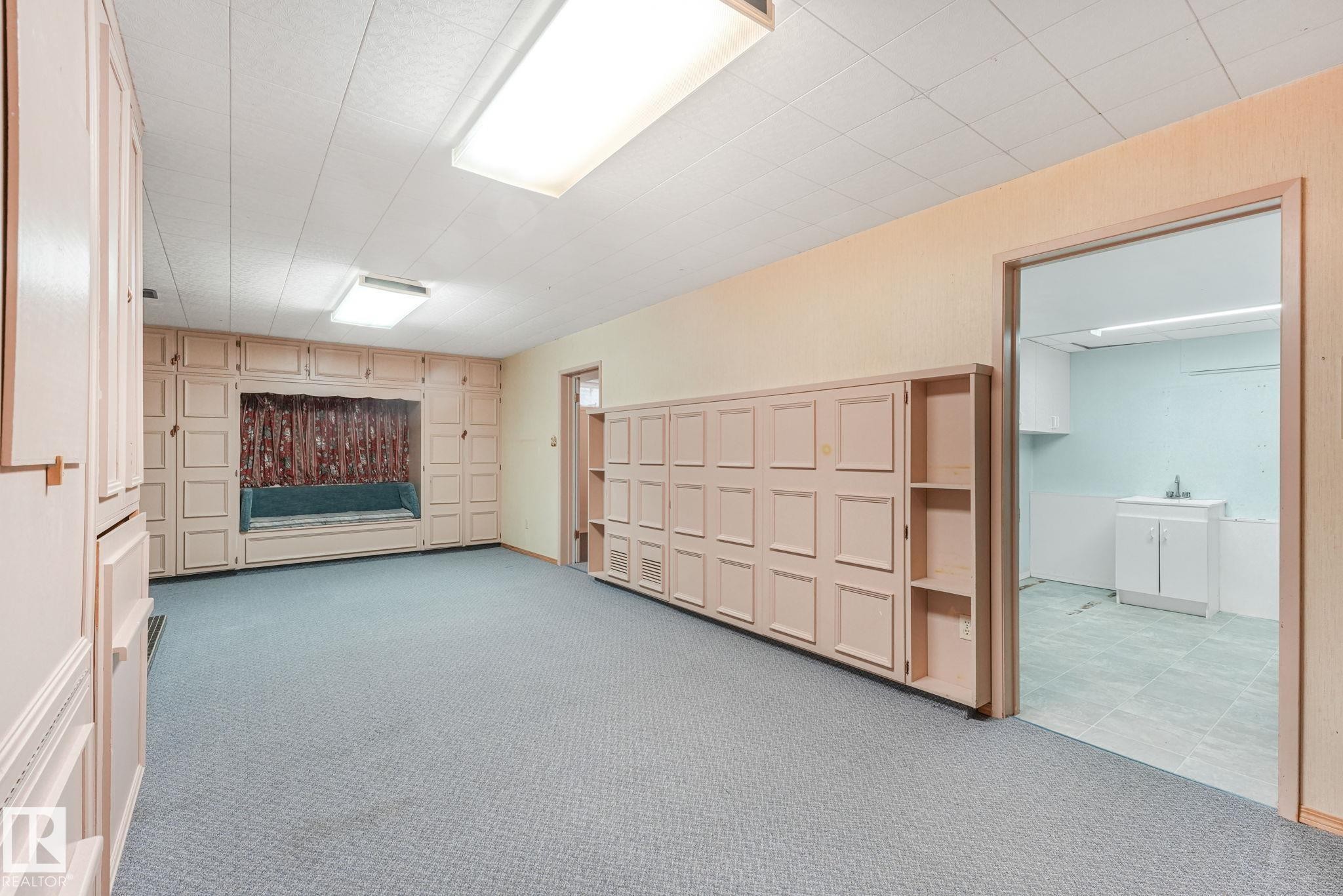 Spacious room featuring extensive built-in cabinetry, a window seat with storage, recessed fluorescent lighting, and wall-to-wall carpeting - 13320 79 Avenue Nw, Edmonton, AB - Indoor Photo Showing Other Room
