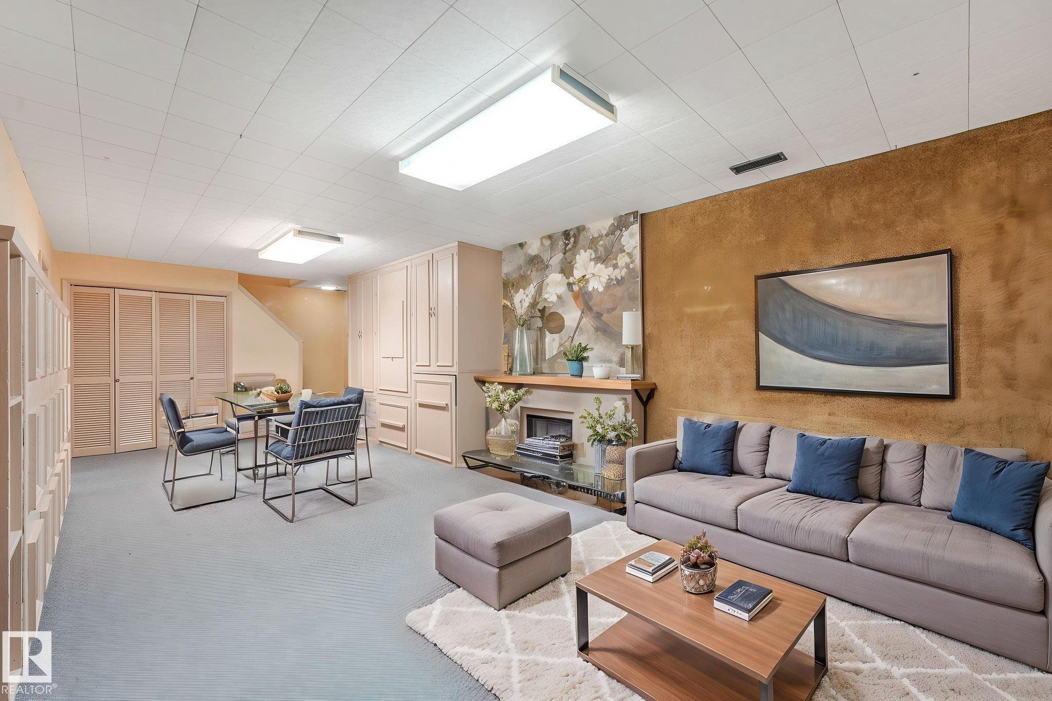 Expansive room featuring light blue carpeting, a textured accent wall, and a built-in fireplace with a stone surround - 13320 79 Avenue Nw, Edmonton, AB - Indoor Photo Showing Living Room With Fireplace