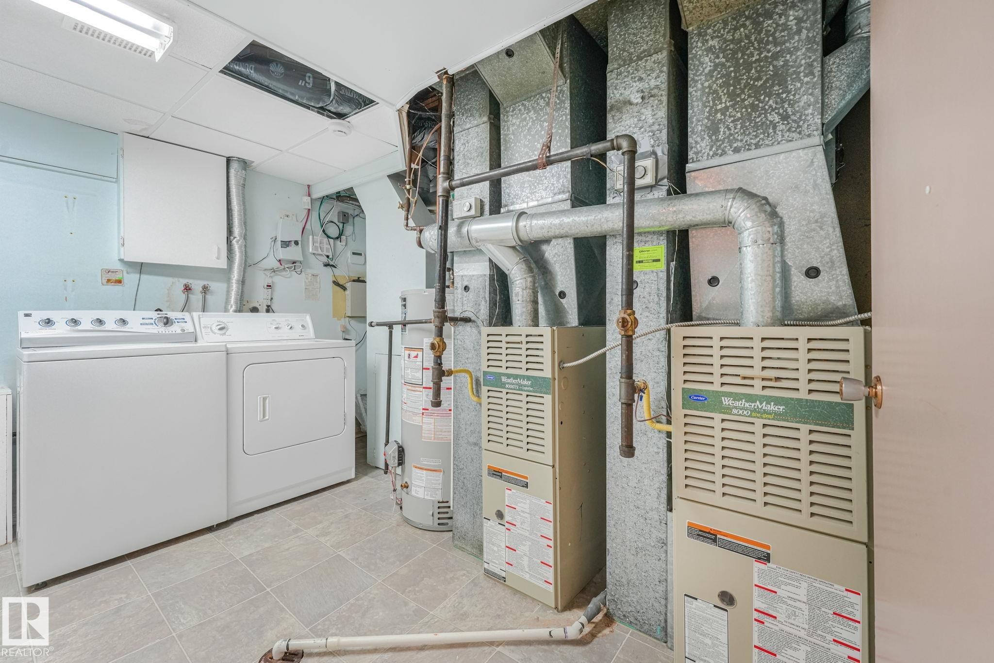 Utility room featuring two furnaces, a hot water heater, and a washer and dryer set - 13320 79 Avenue Nw, Edmonton, AB - Indoor Photo Showing Laundry Room