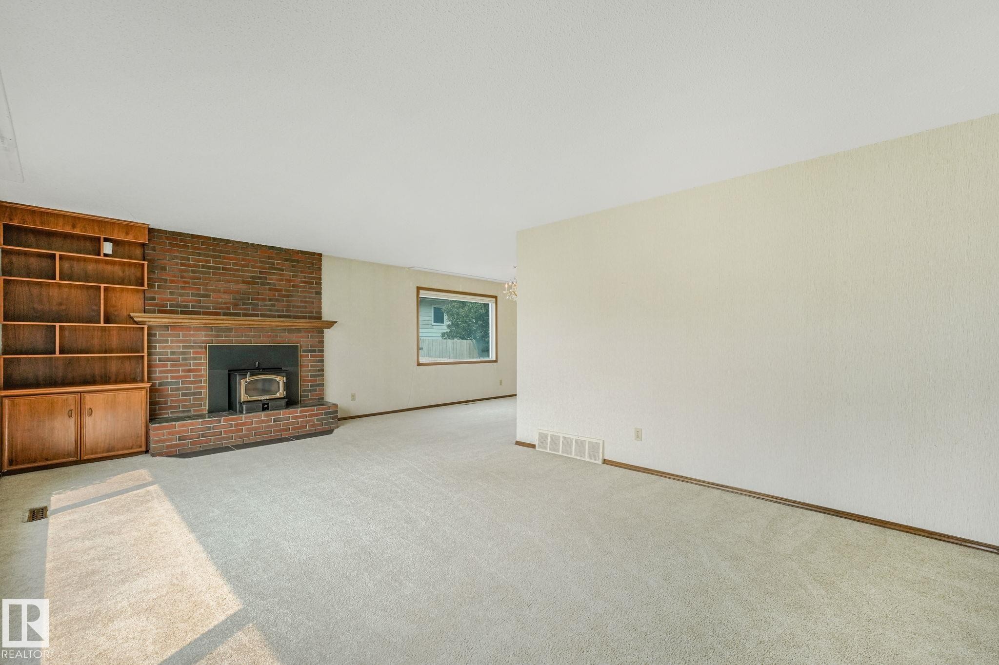Spacious room featuring a brick fireplace with a wood-burning insert and a wood mantle - 13320 79 Avenue Nw, Edmonton, AB - Indoor With Fireplace
