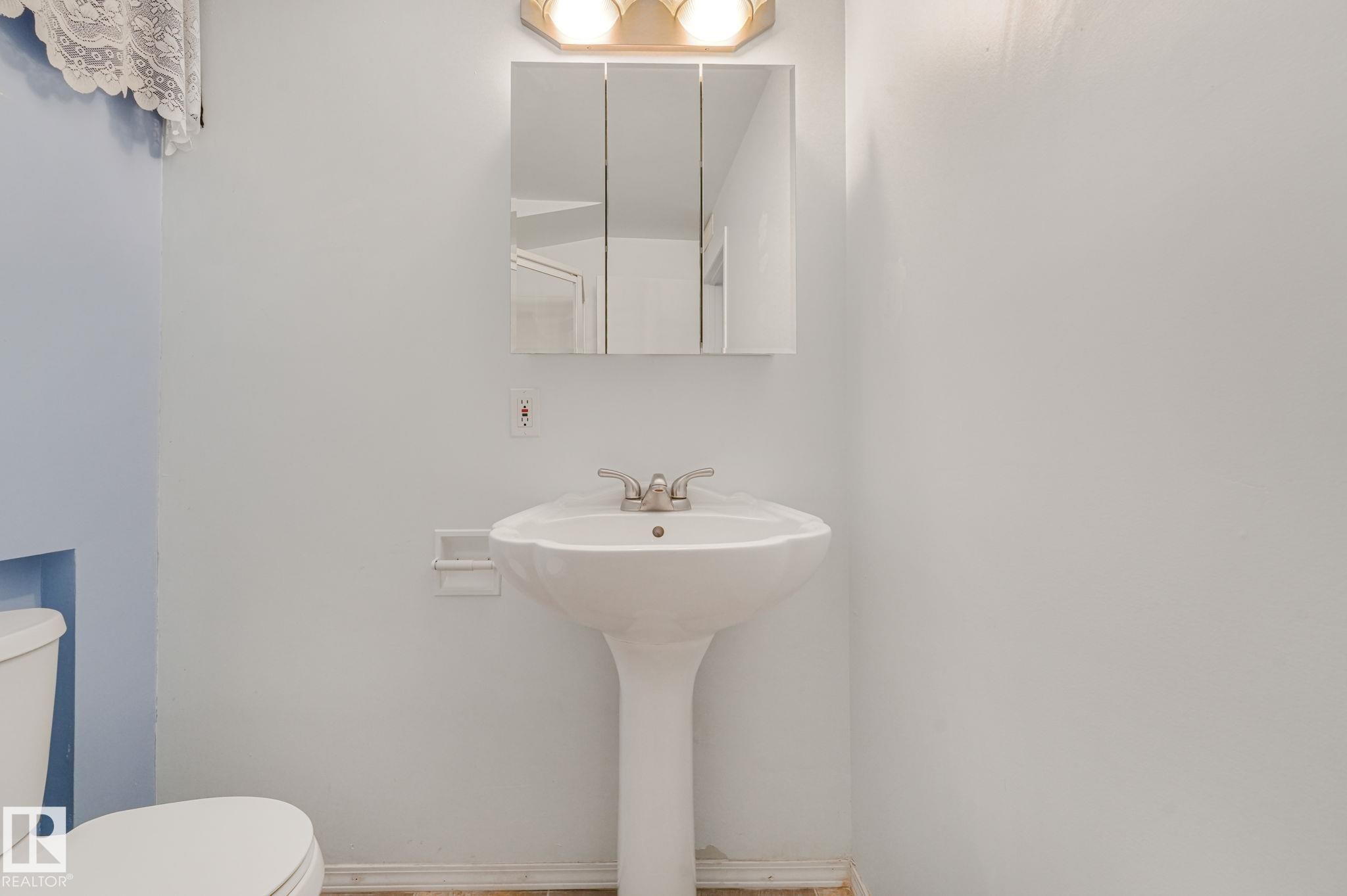 Pedestal sink with a two-handle faucet and a wall-mounted medicine cabinet - 13320 79 Avenue Nw, Edmonton, AB - Indoor Photo Showing Bathroom