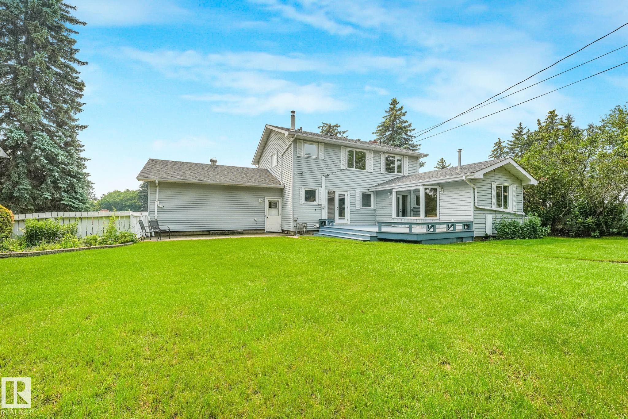 Expansive green lawn with a two-story residence featuring light gray siding - 13320 79 Avenue Nw, Edmonton, AB - Outdoor