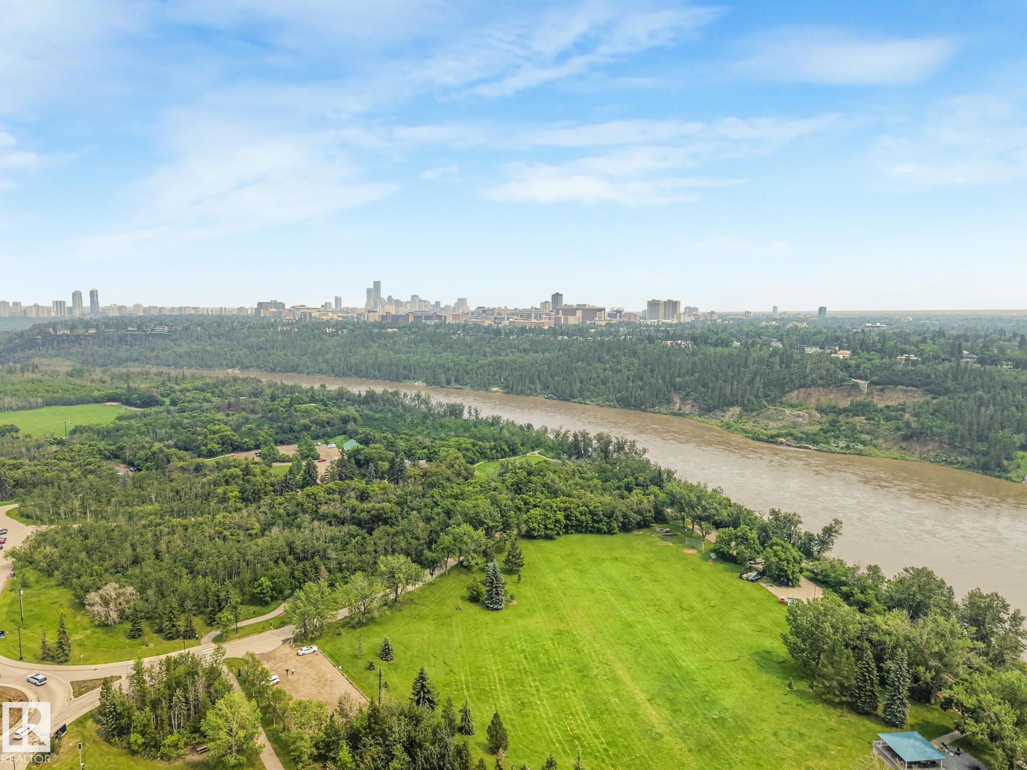 Aerial perspective showcasing expansive green spaces, mature tree coverage, a broad river, and a distant cityscape under a clear sky - 13320 79 Avenue Nw, Edmonton, AB - Outdoor With View