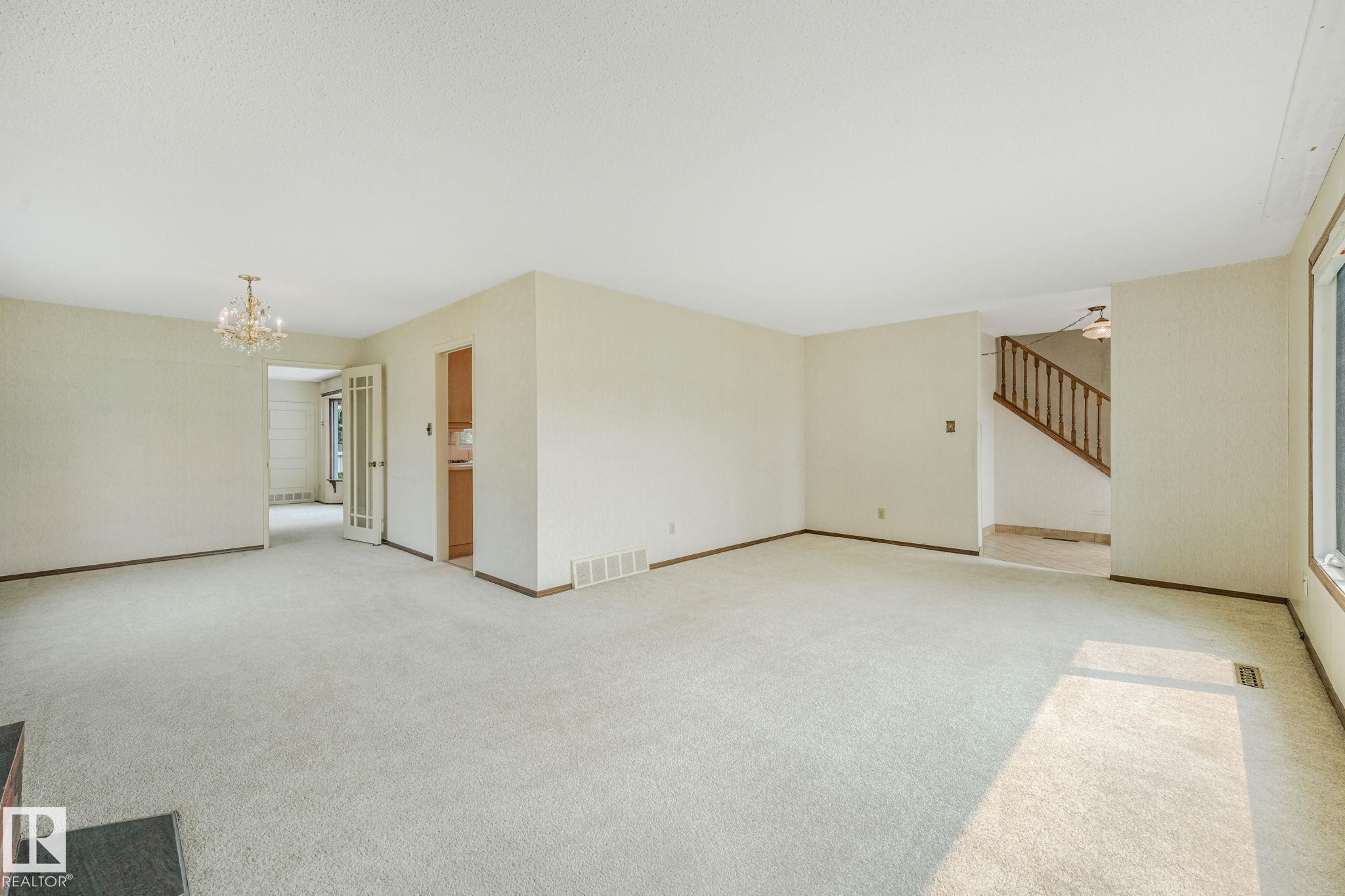 Spacious living area featuring light-colored carpeting and neutral wall tones - 13320 79 Avenue Nw, Edmonton, AB - Indoor Photo Showing Other Room