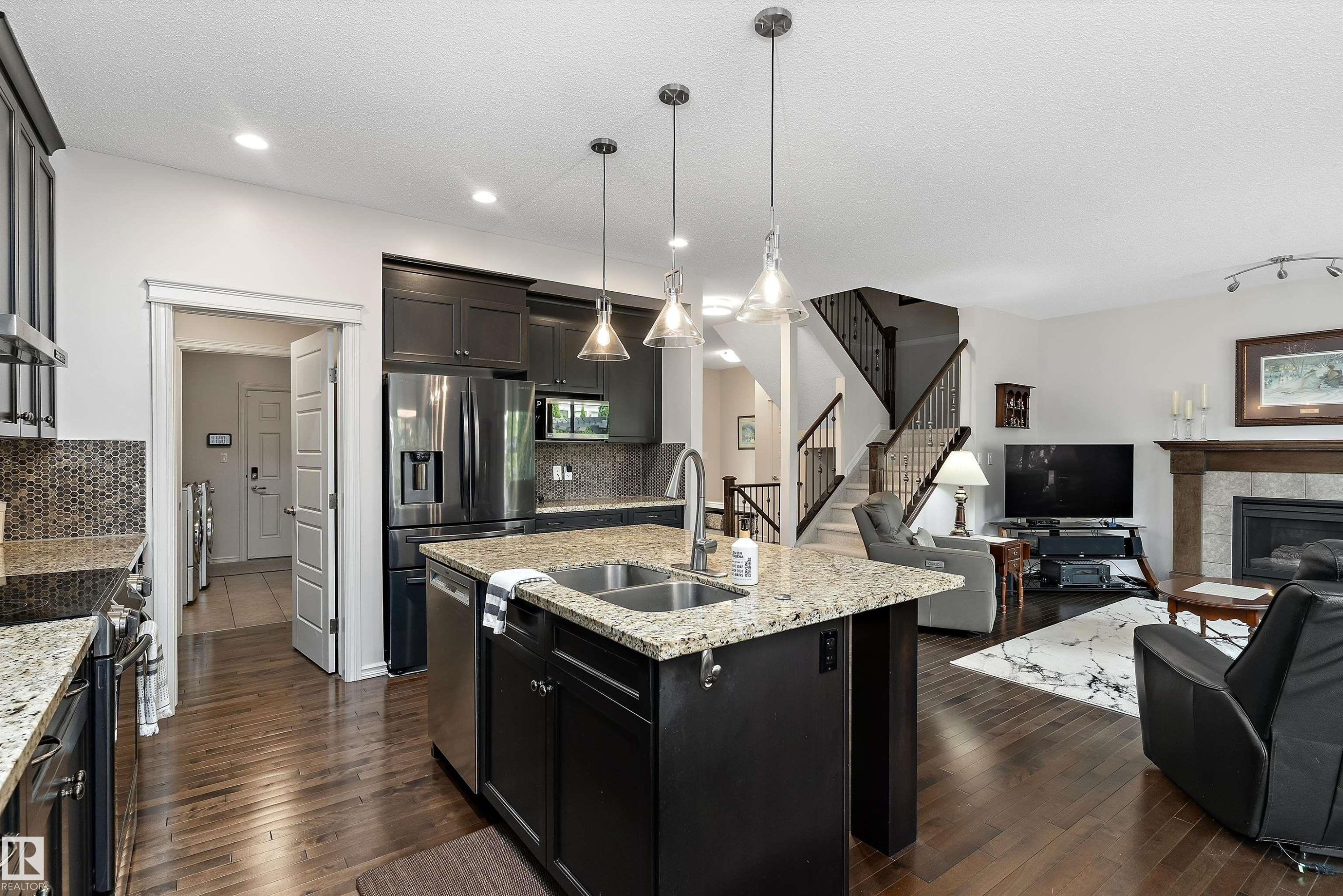 Open-concept kitchen featuring dark wood cabinetry, granite countertops, and stainless steel appliances - 1097 Armitage Crescent, Edmonton, AB