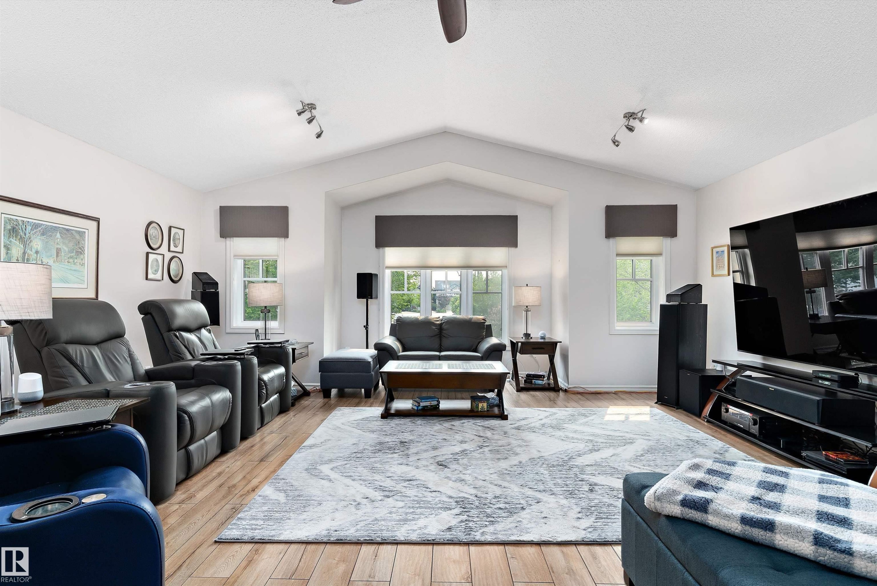 Vaulted ceiling with architectural detailing, wood-finish flooring, multiple windows, track lighting, and a ceiling fan - 1097 Armitage Crescent, Edmonton, AB
