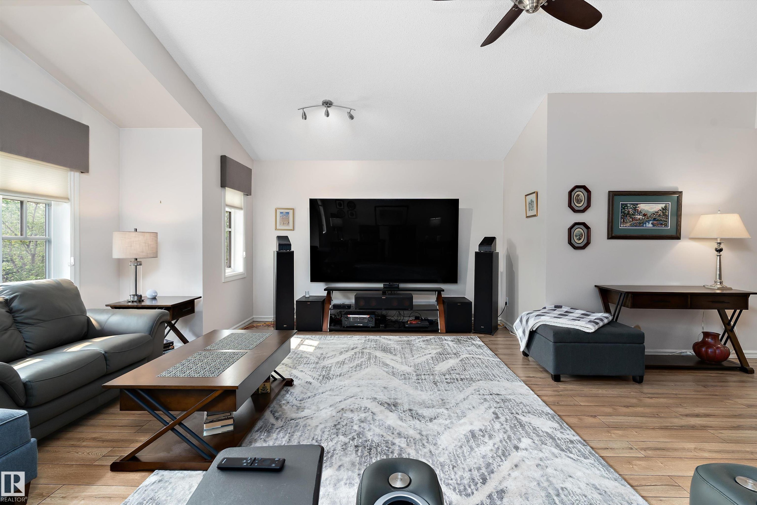 Spacious living area featuring wood-finish flooring, vaulted ceilings, and a ceiling fan - 1097 Armitage Crescent, Edmonton, AB